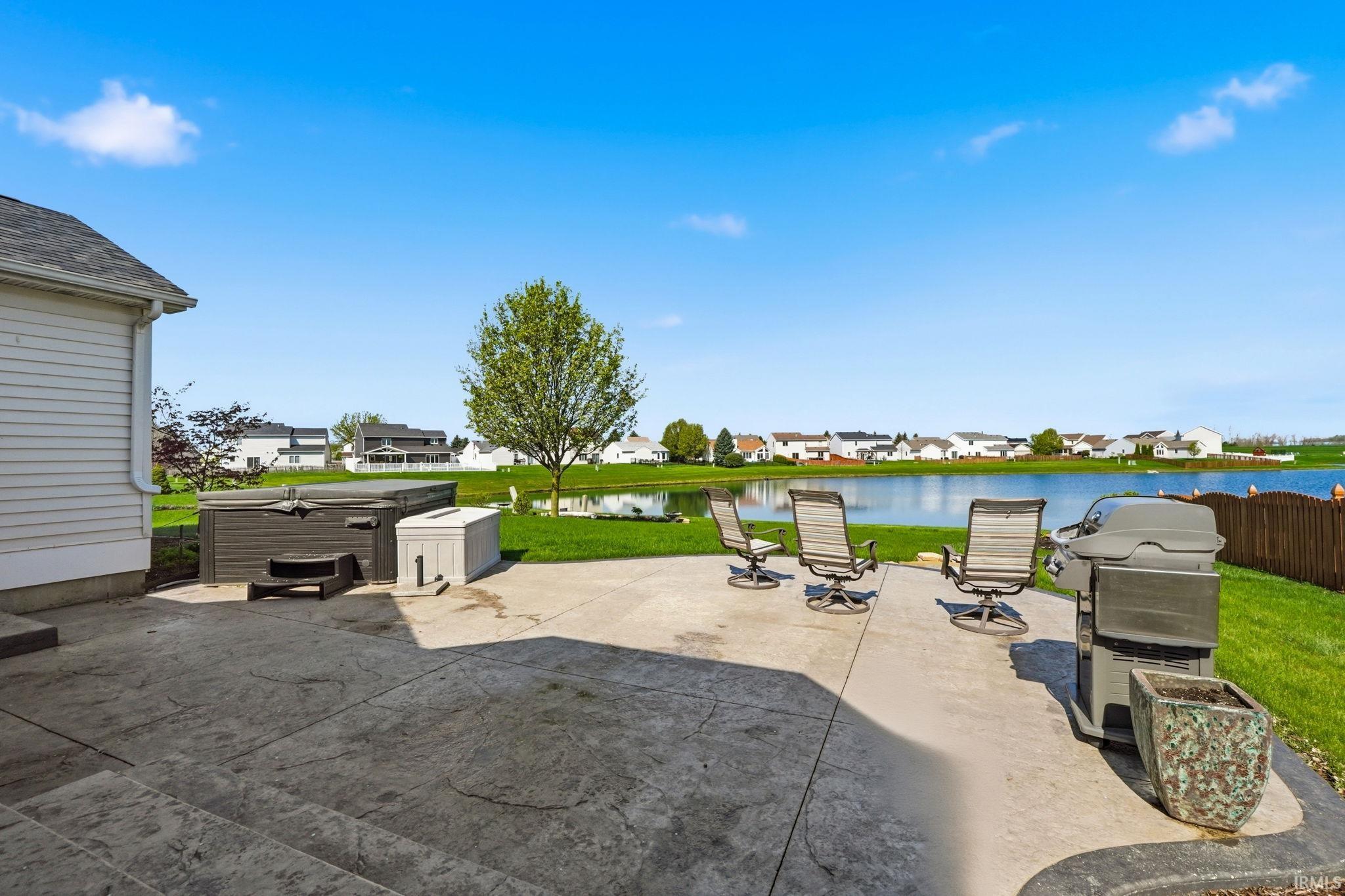 Spacious stamped concrete patio overlooking a tranquil pond with expansive green space