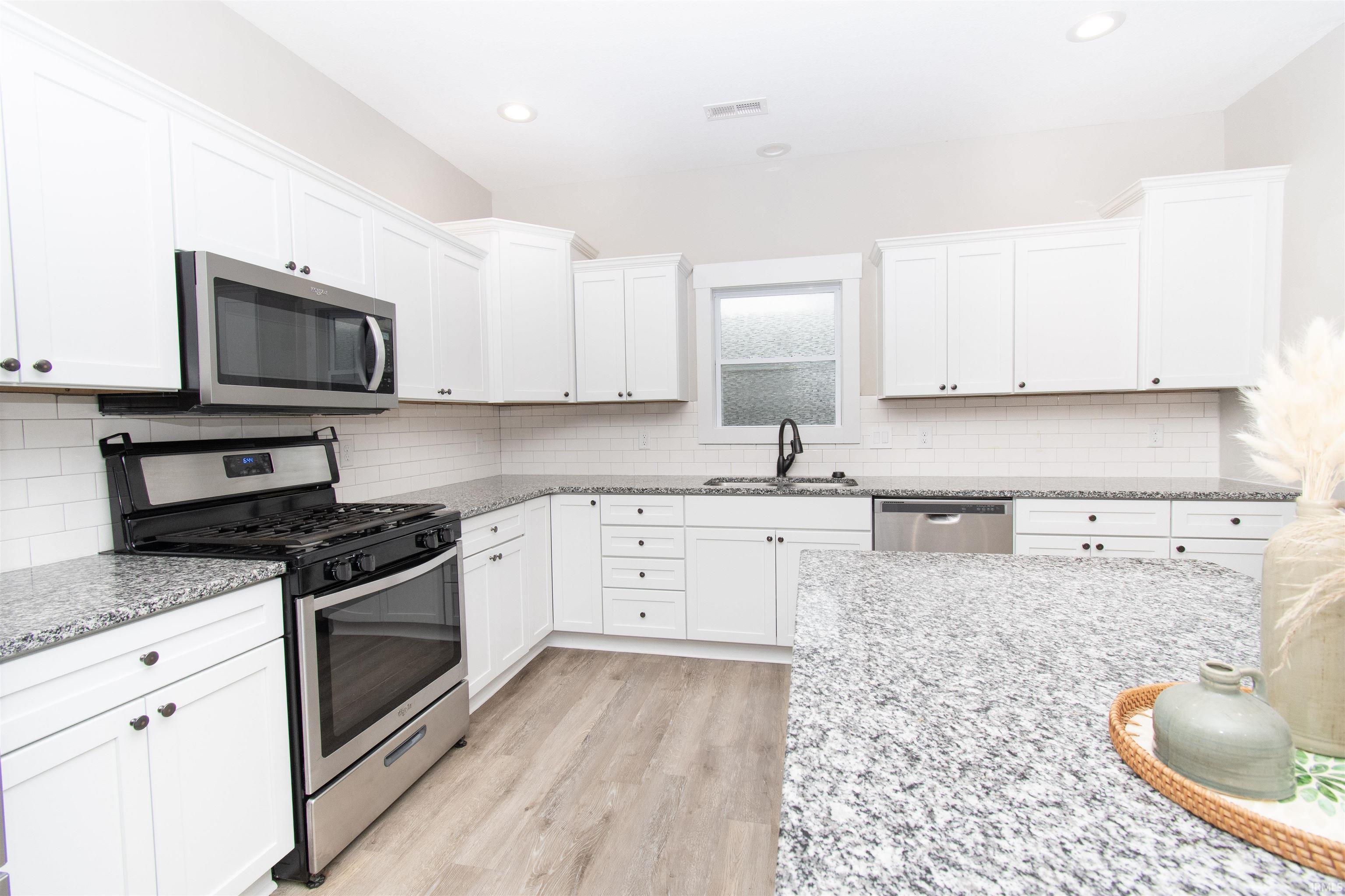 Modern kitchen featuring light wood-finish flooring and white cabinetry