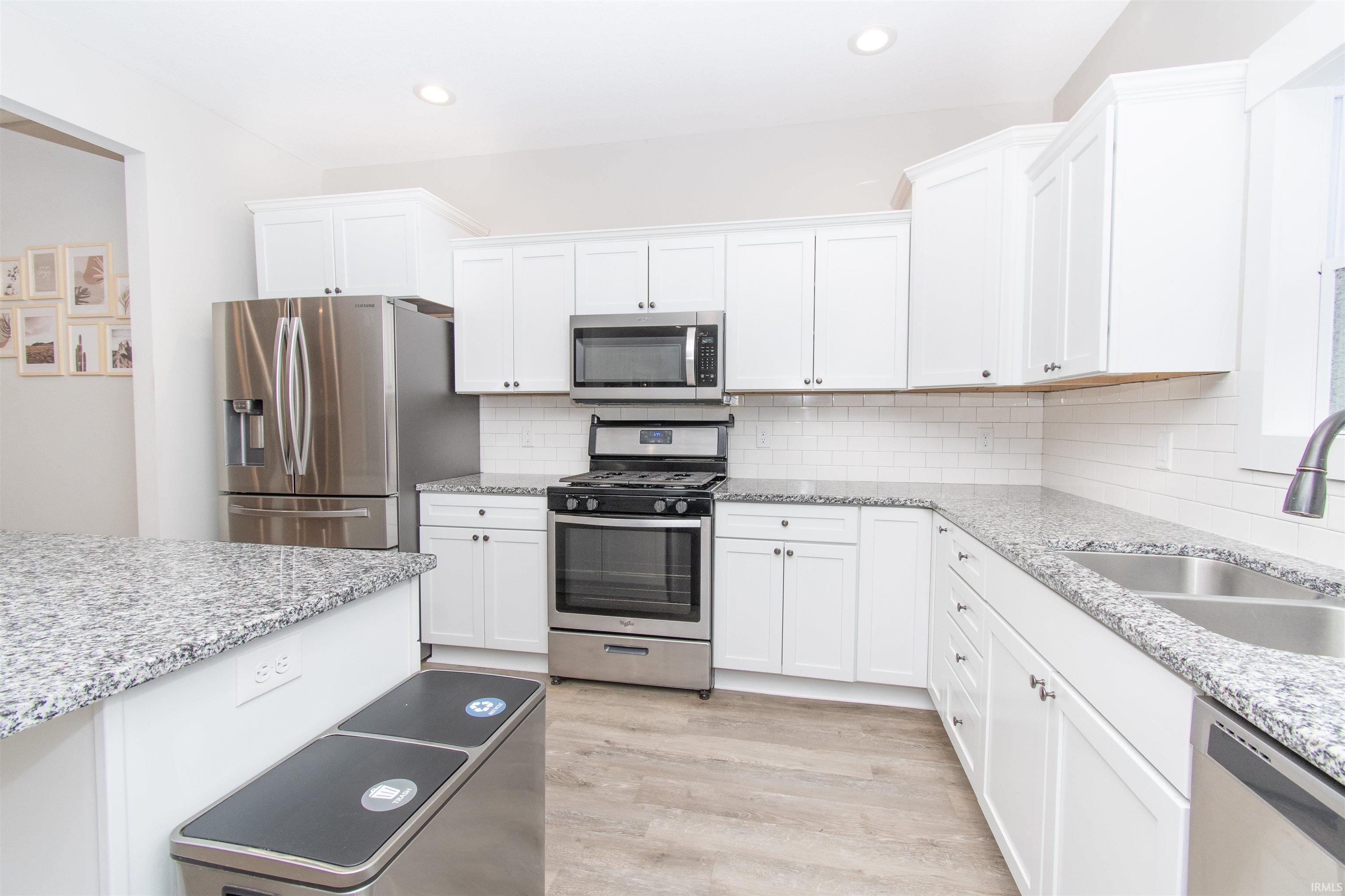 Kitchen featuring white shaker cabinetry, stainless steel appliances, granite countertops, and subway tile backsplash