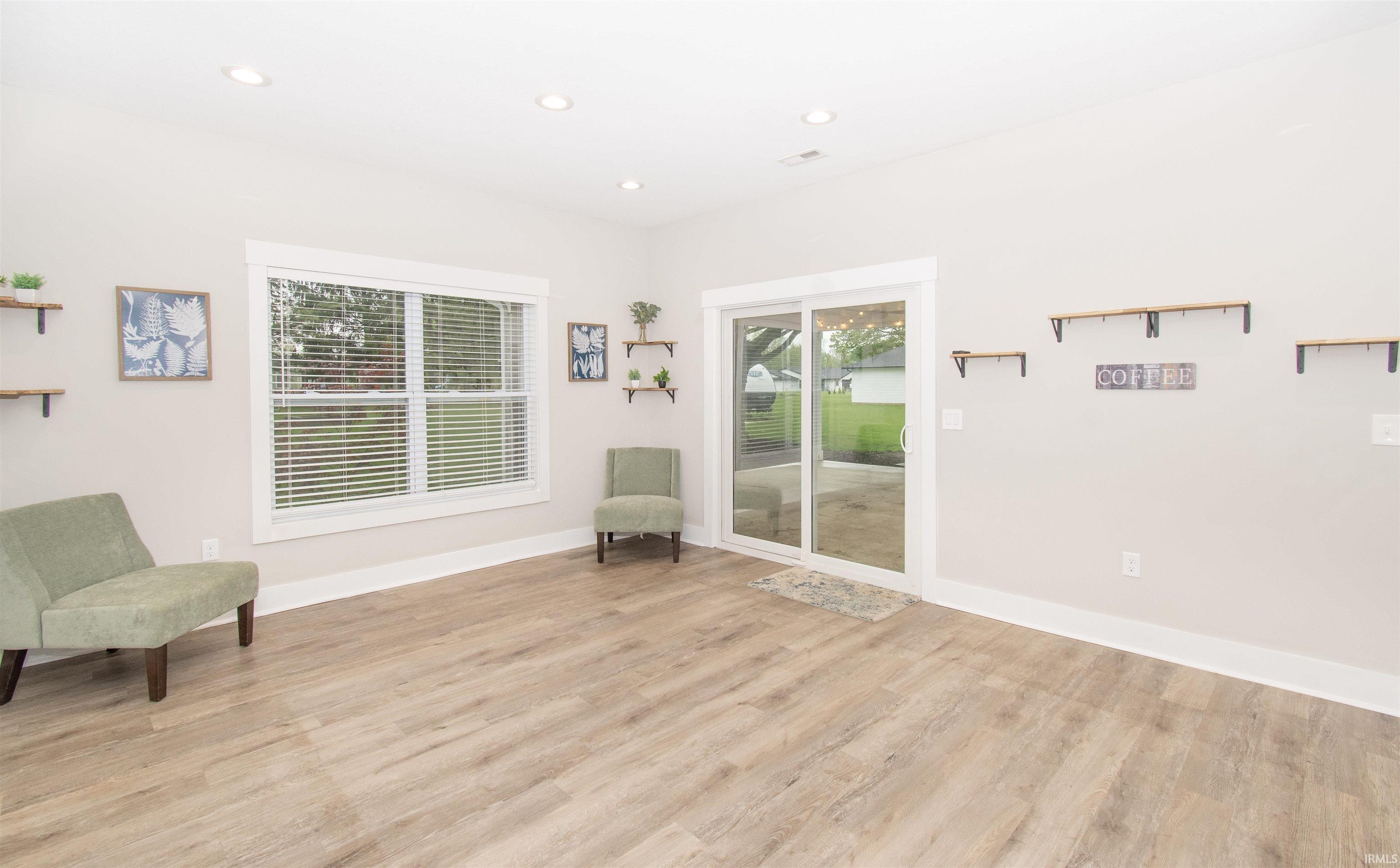 Spacious interior room featuring wood-finish flooring, recessed lighting, and white baseboards