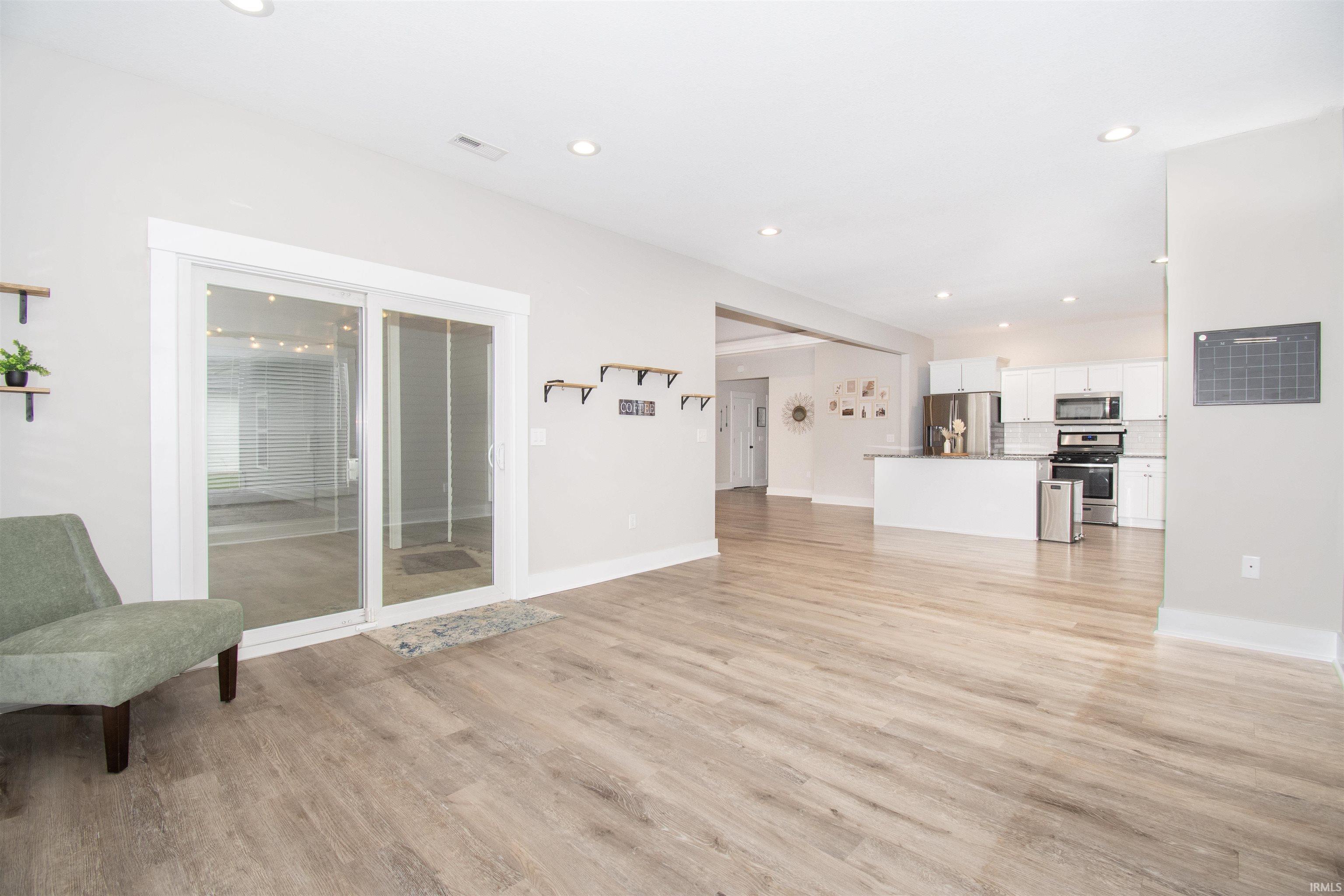 Open-concept living space featuring wood-finish flooring, recessed lighting, and a sliding glass door