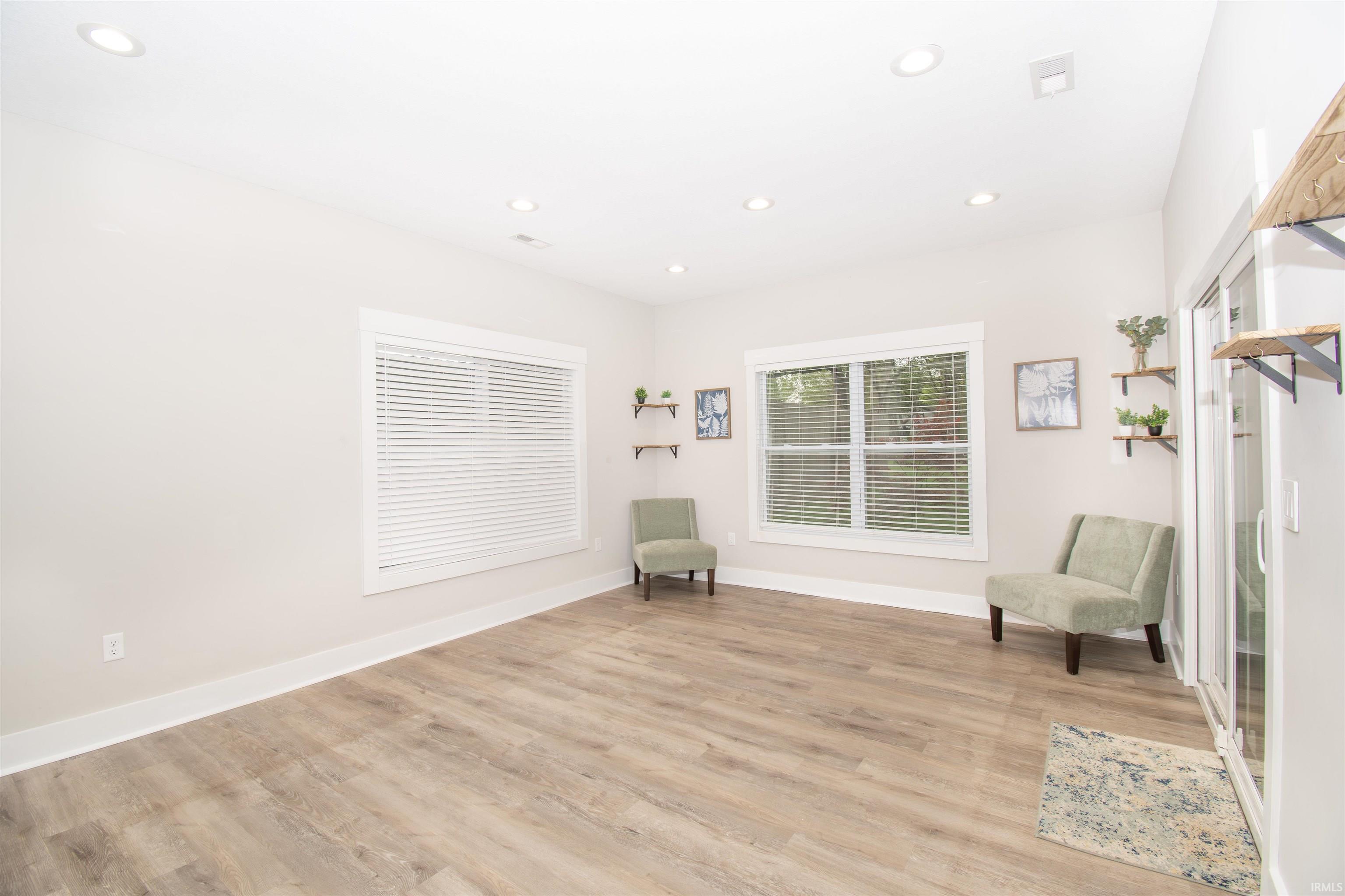 Spacious interior featuring wood-finish flooring, recessed lighting, and ample natural illumination from multiple windows