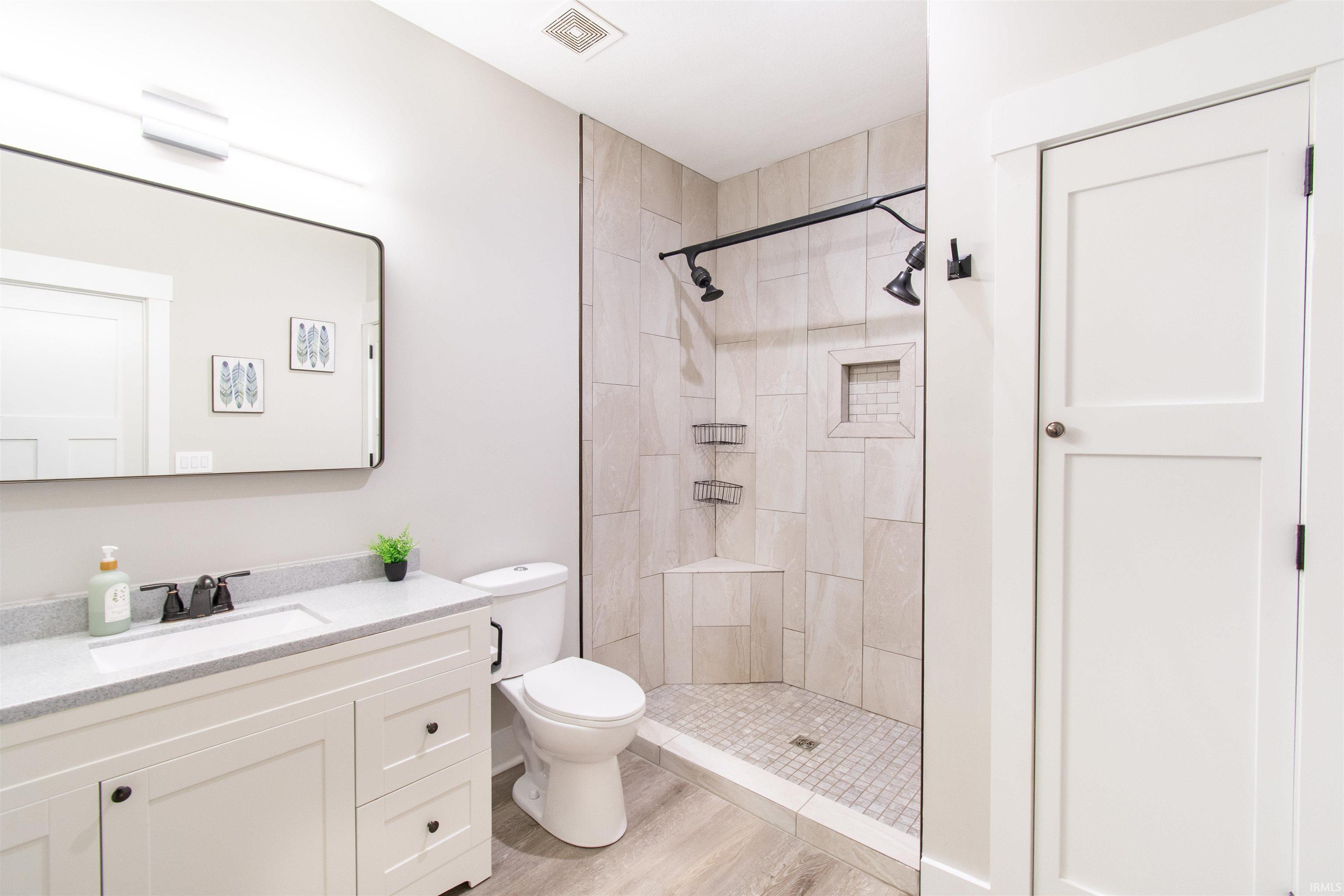 Shower with light-toned wall tile, a built-in shower niche, and a corner bench
