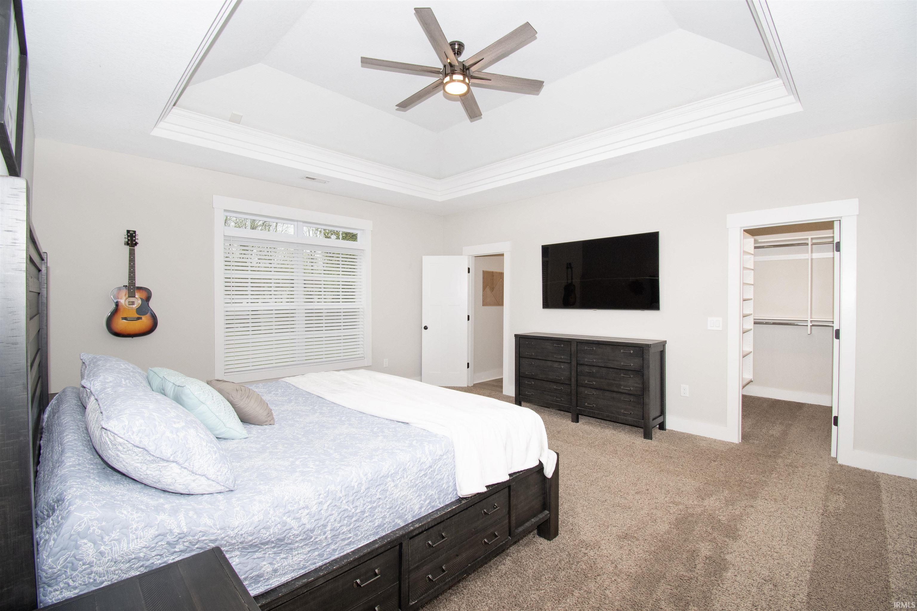 Bedroom featuring a tray ceiling with crown molding, ceiling fan, and carpet flooring