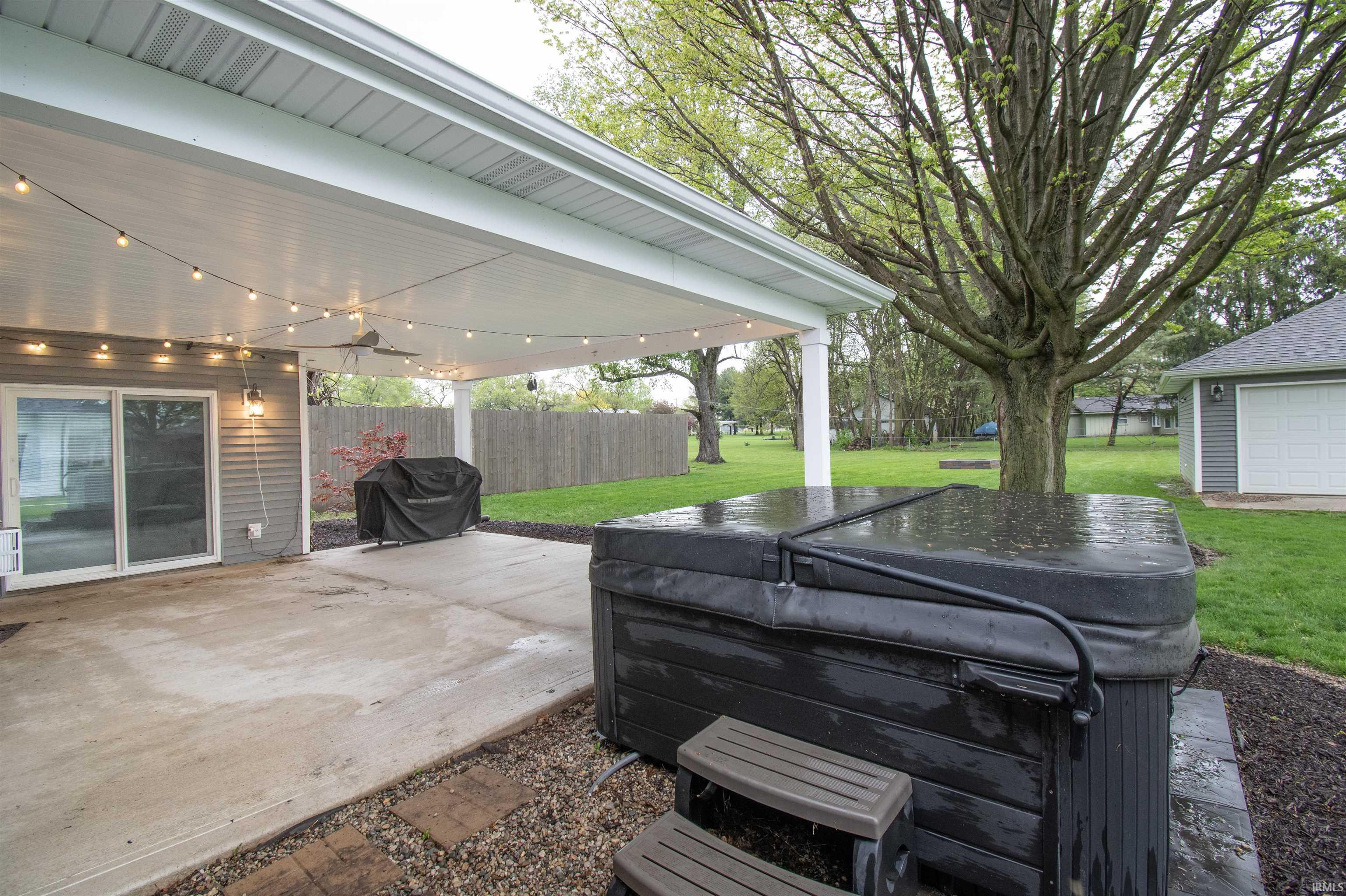 Covered patio featuring string lighting, a ceiling fan, and sliding glass door access