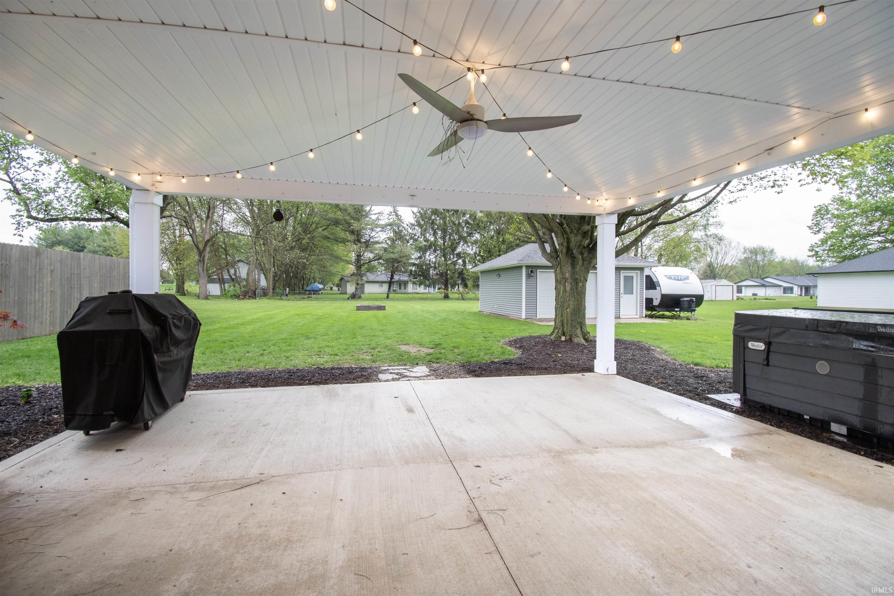 Expansive covered patio featuring a ceiling fan, string lighting, and concrete flooring