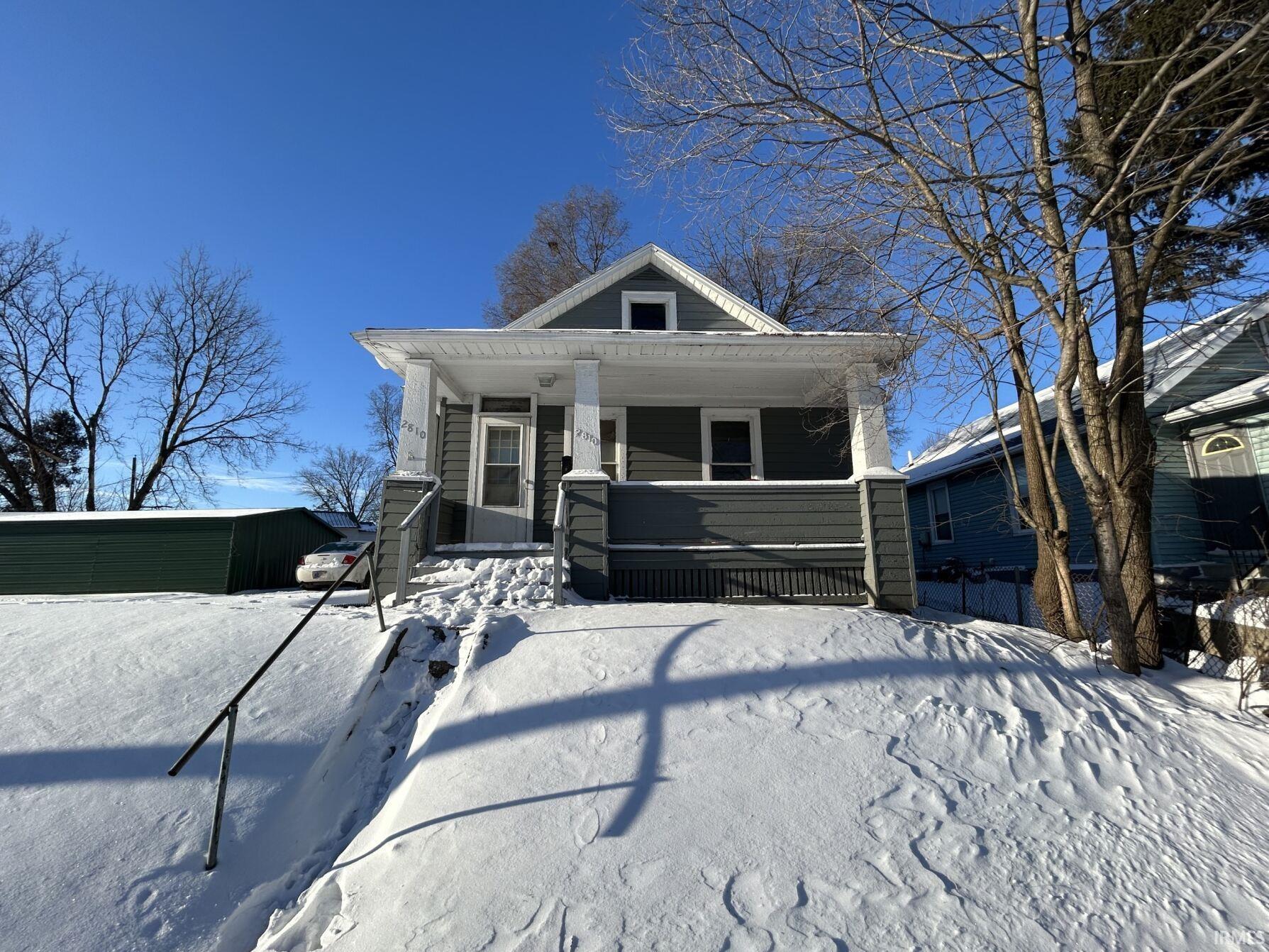 Front facade featuring a covered porch with white columns, dark gray siding, and a gabled roof