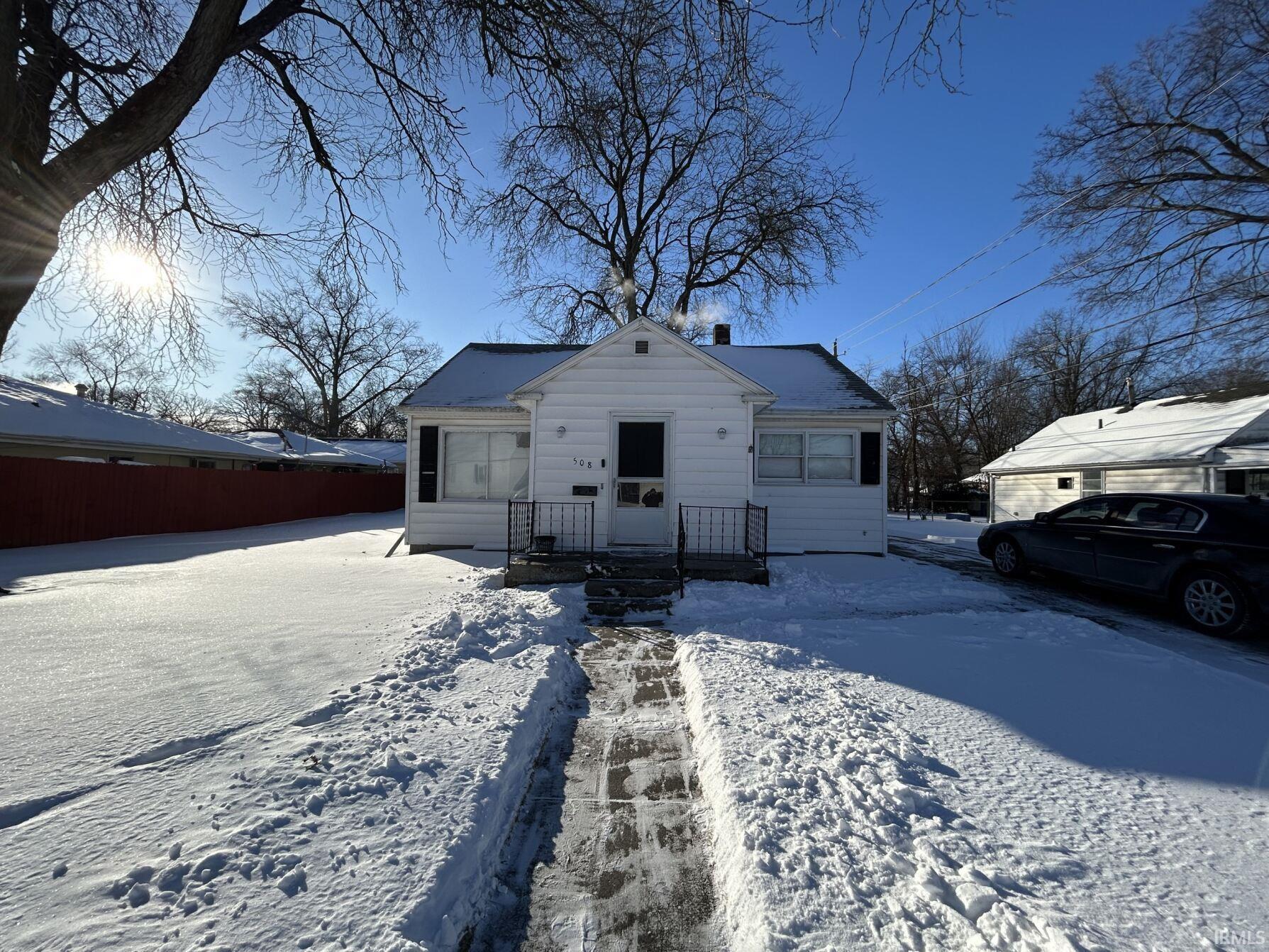 White clapboard siding exterior with a dark roof and black window shutters