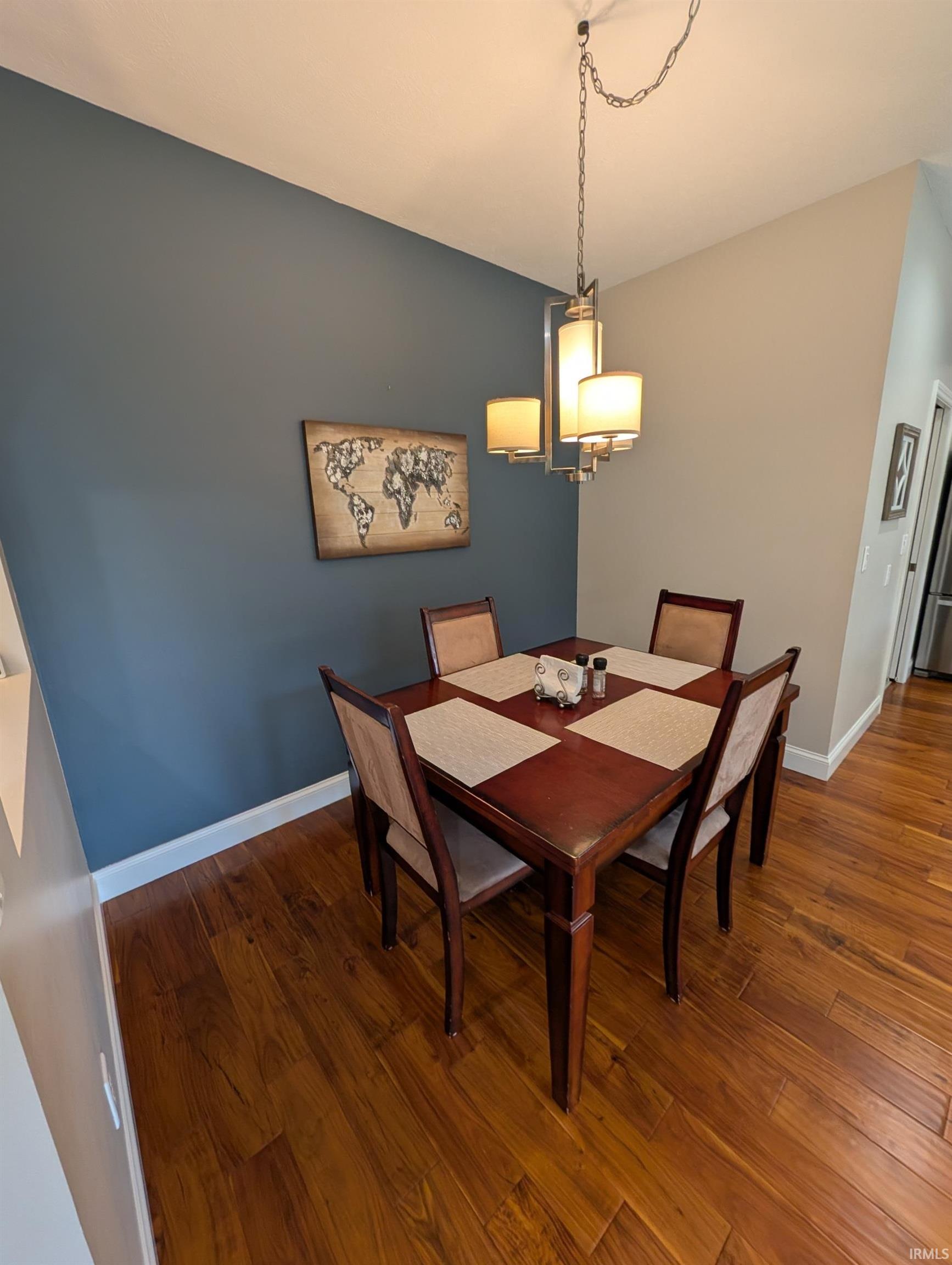 Dining area featuring a contemporary chandelier, wood-finish flooring, a two-tone wall treatment, and white baseboards