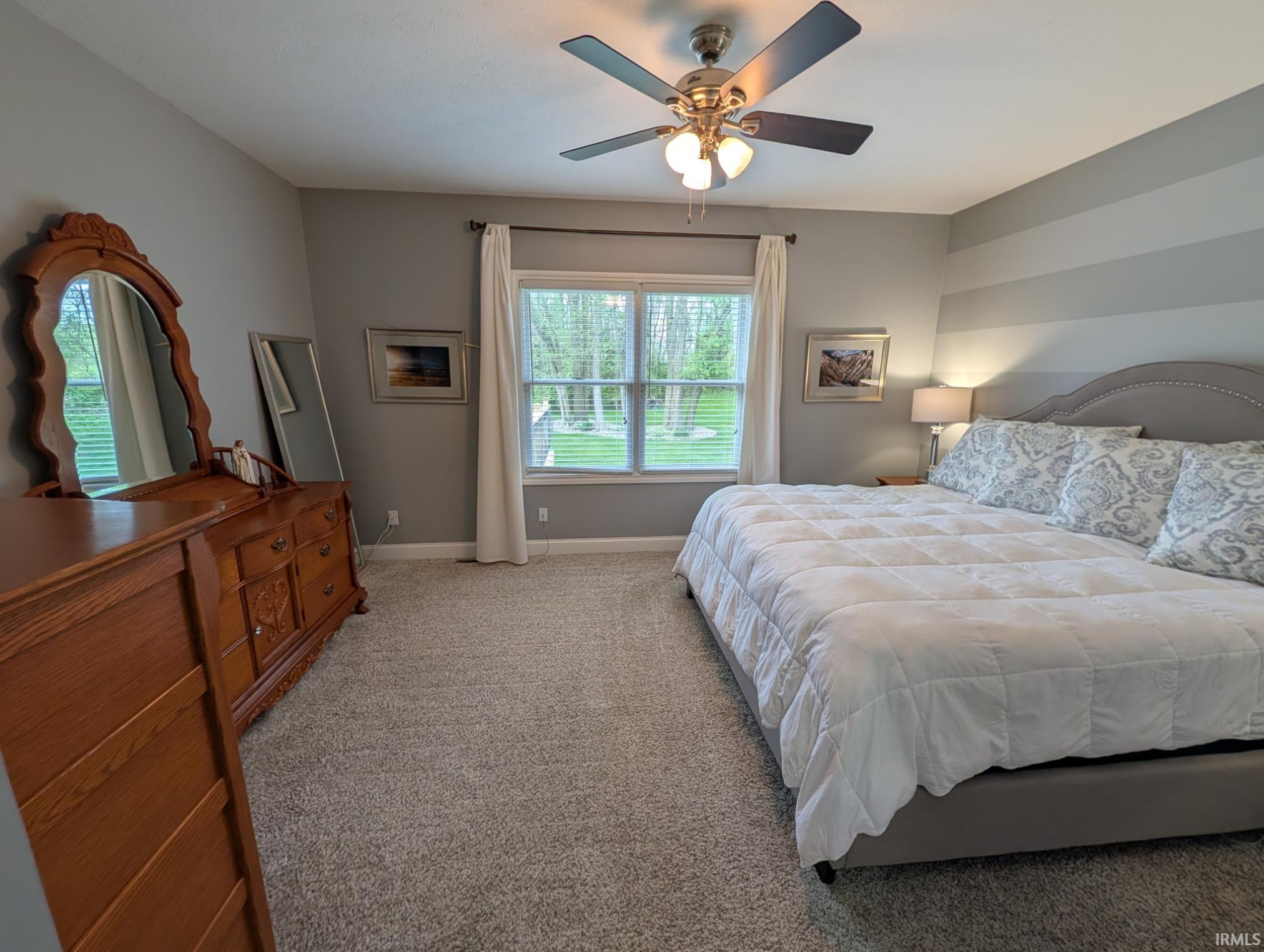 Carpeted room featuring a ceiling fan with integrated lighting, a large window with blinds, and light gray walls