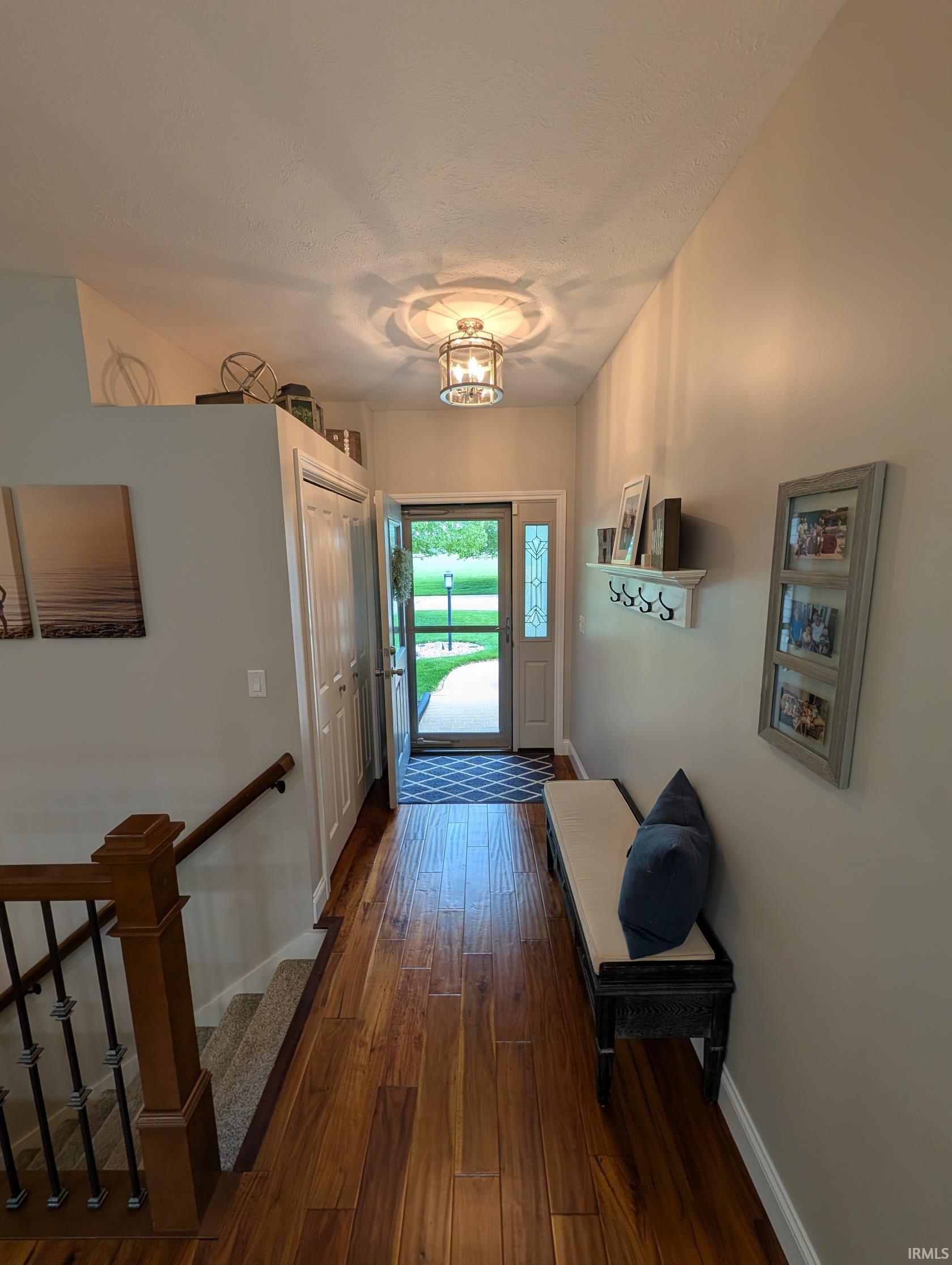 Inviting entryway featuring wood-finish flooring, a decorative glass-paneled front door, and a built-in coat closet