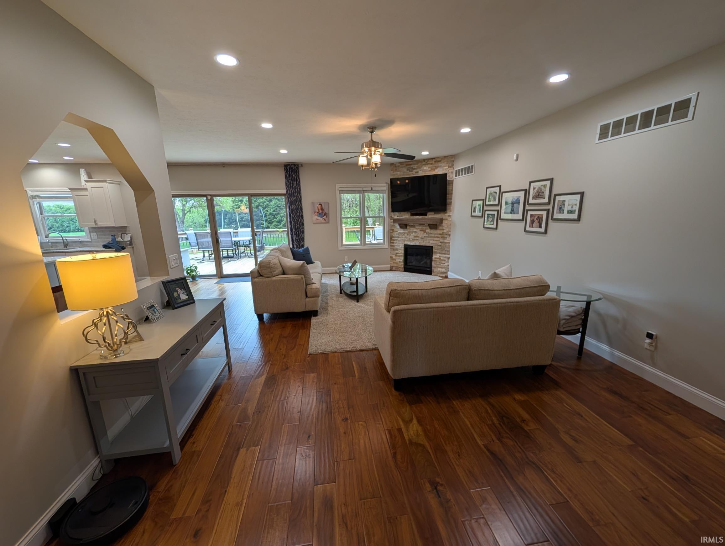 Spacious living area featuring wood-finish flooring, recessed lighting, and a stone-clad fireplace