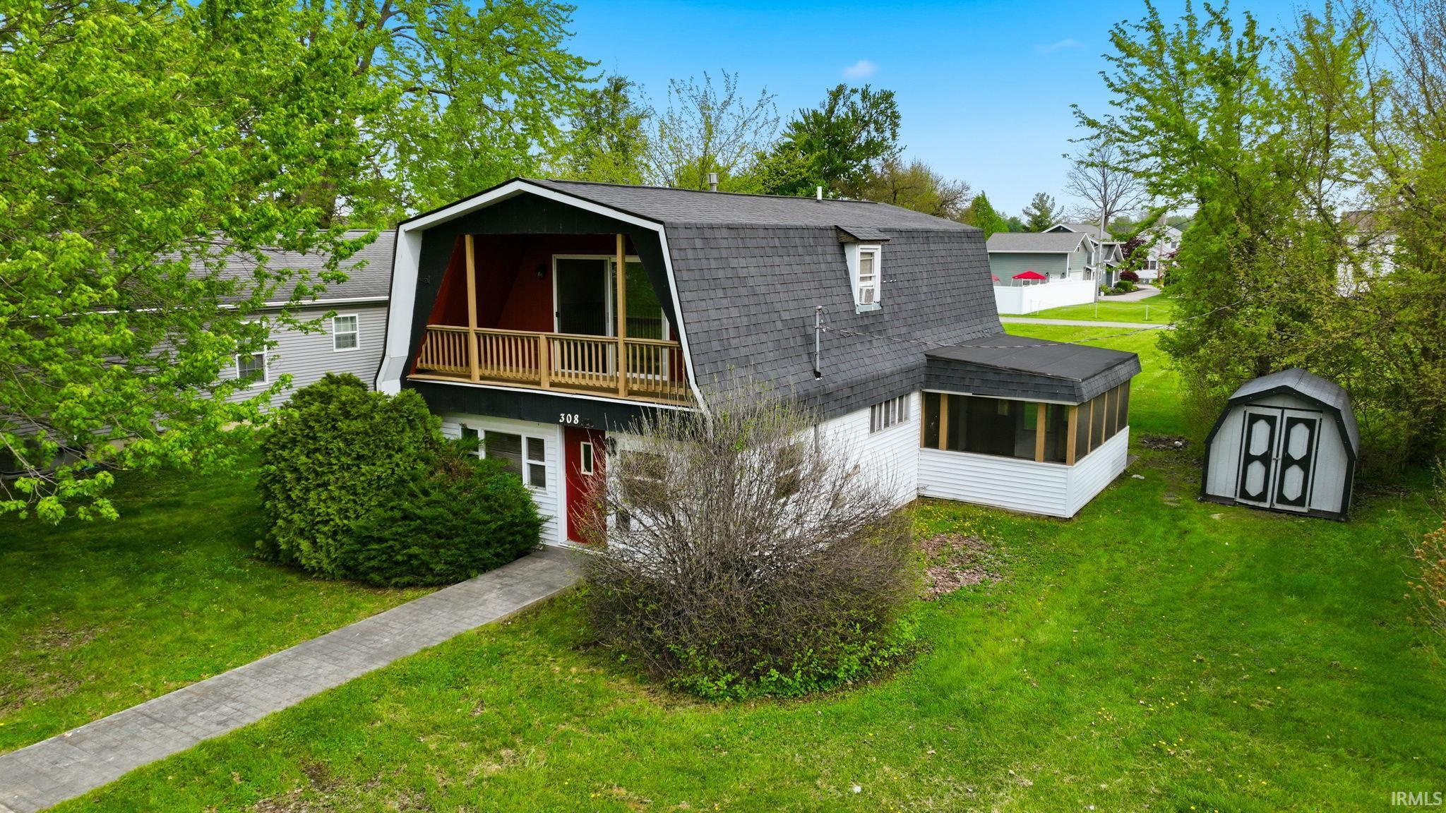 Gambrel roofline property featuring a screened porch and a second-story balcony with wood railing