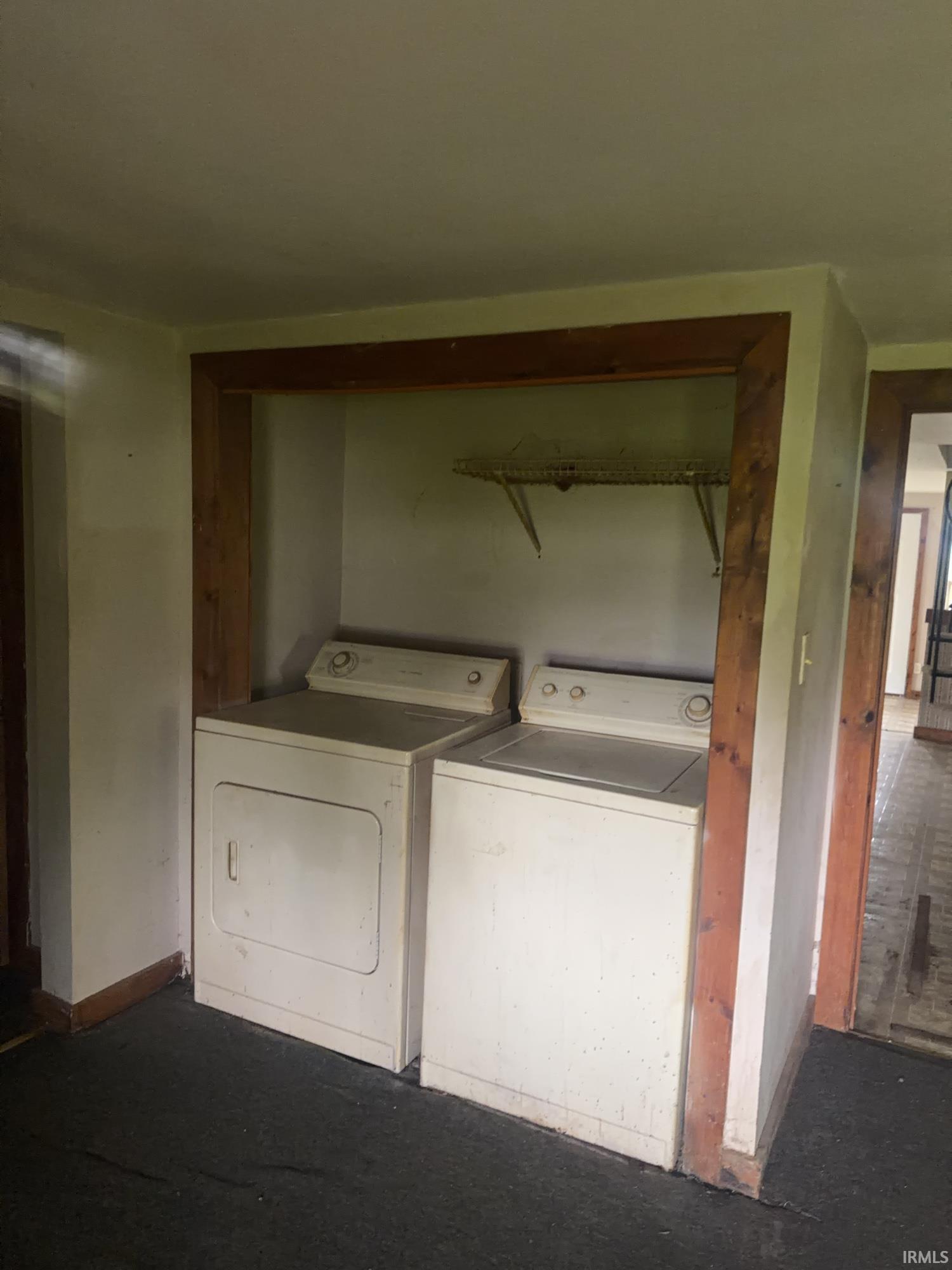 Dedicated laundry area featuring a washer and dryer within a recessed alcove with wood-finish trim