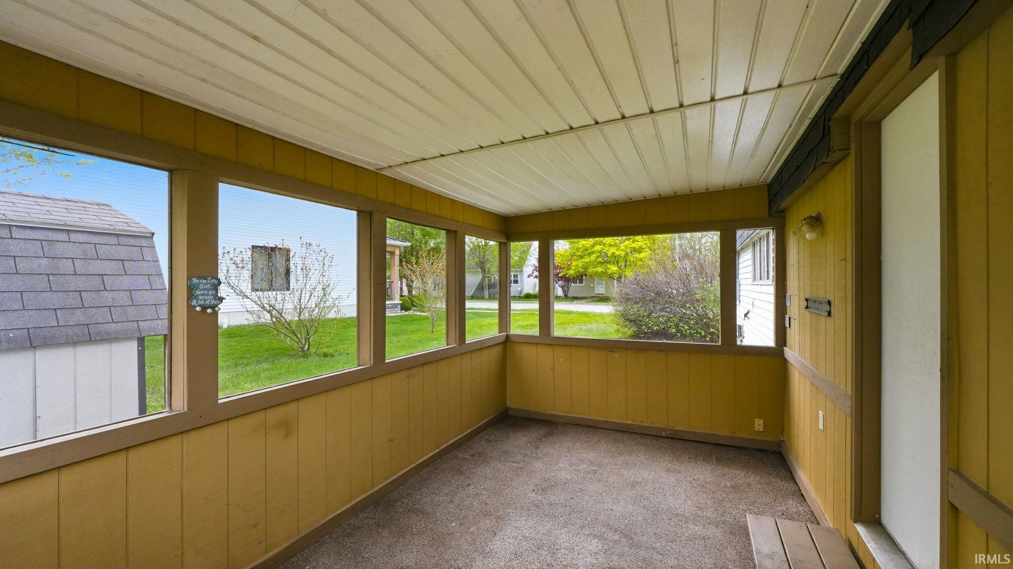 Enclosed porch featuring multiple windows, a paneled ceiling, and carpeting