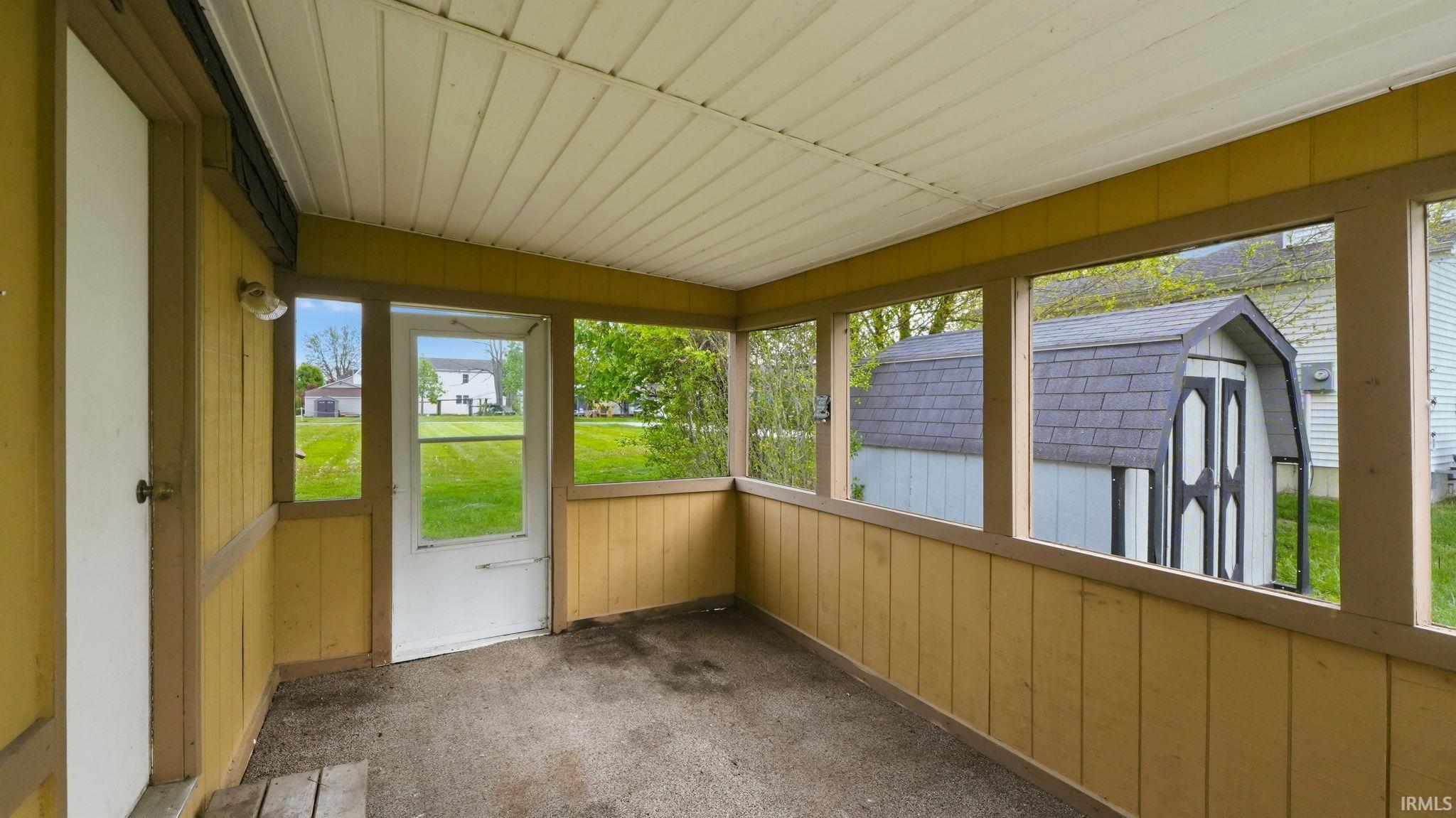 Enclosed porch featuring a paneled wood ceiling and outdoor lighting fixture