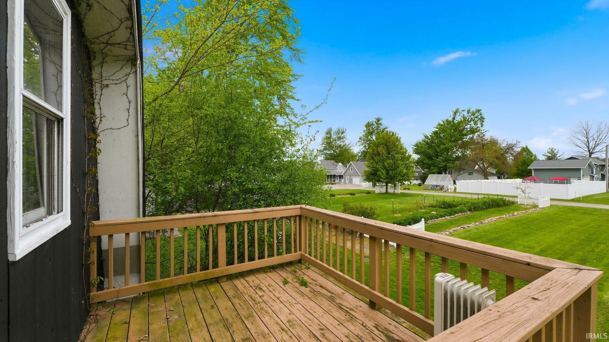 Expansive outdoor deck with natural wood railing overlooking a lush green lawn and garden area