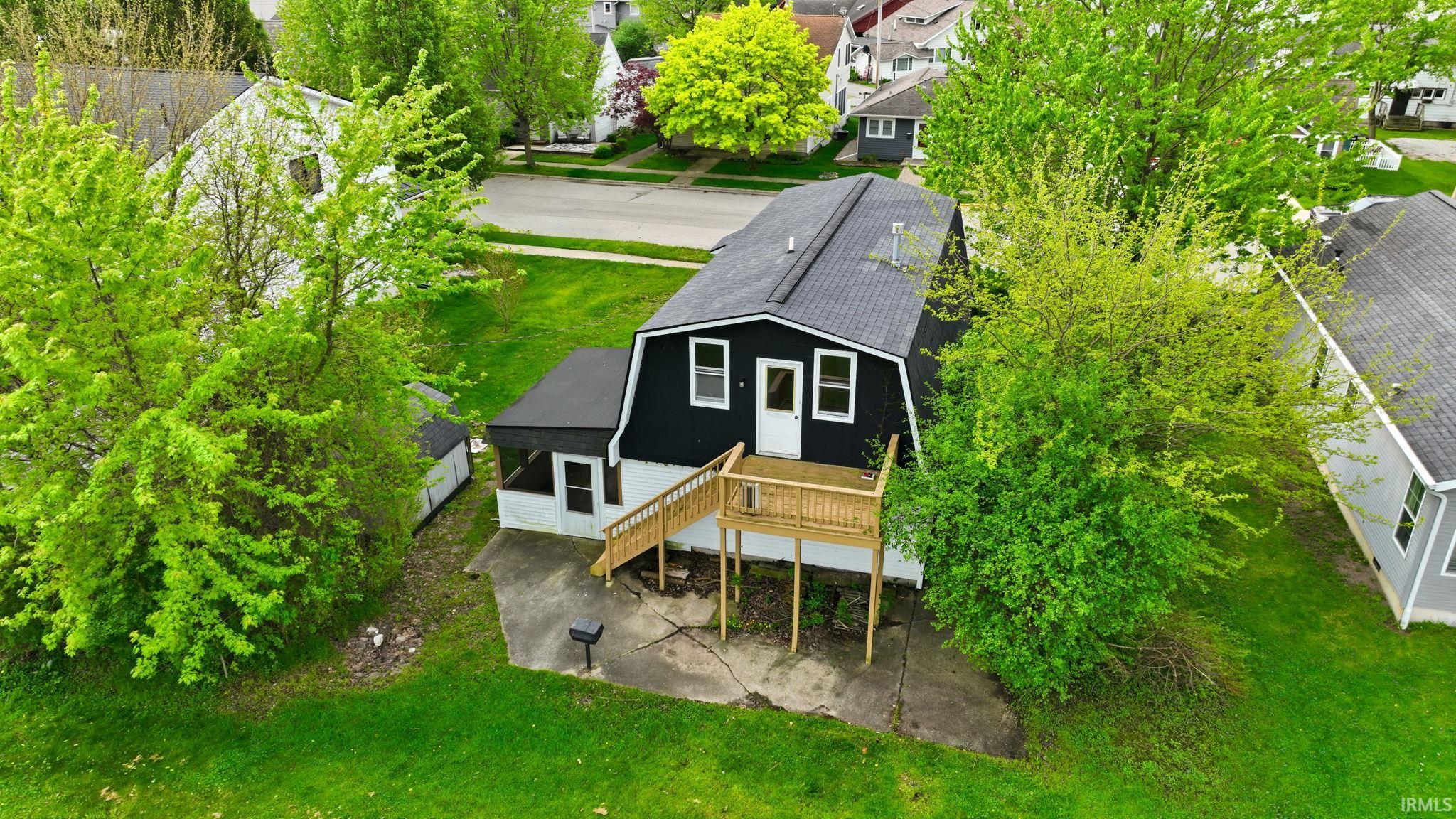 Black exterior with white trim, featuring a gambrel roof and a second-story deck with wooden railing