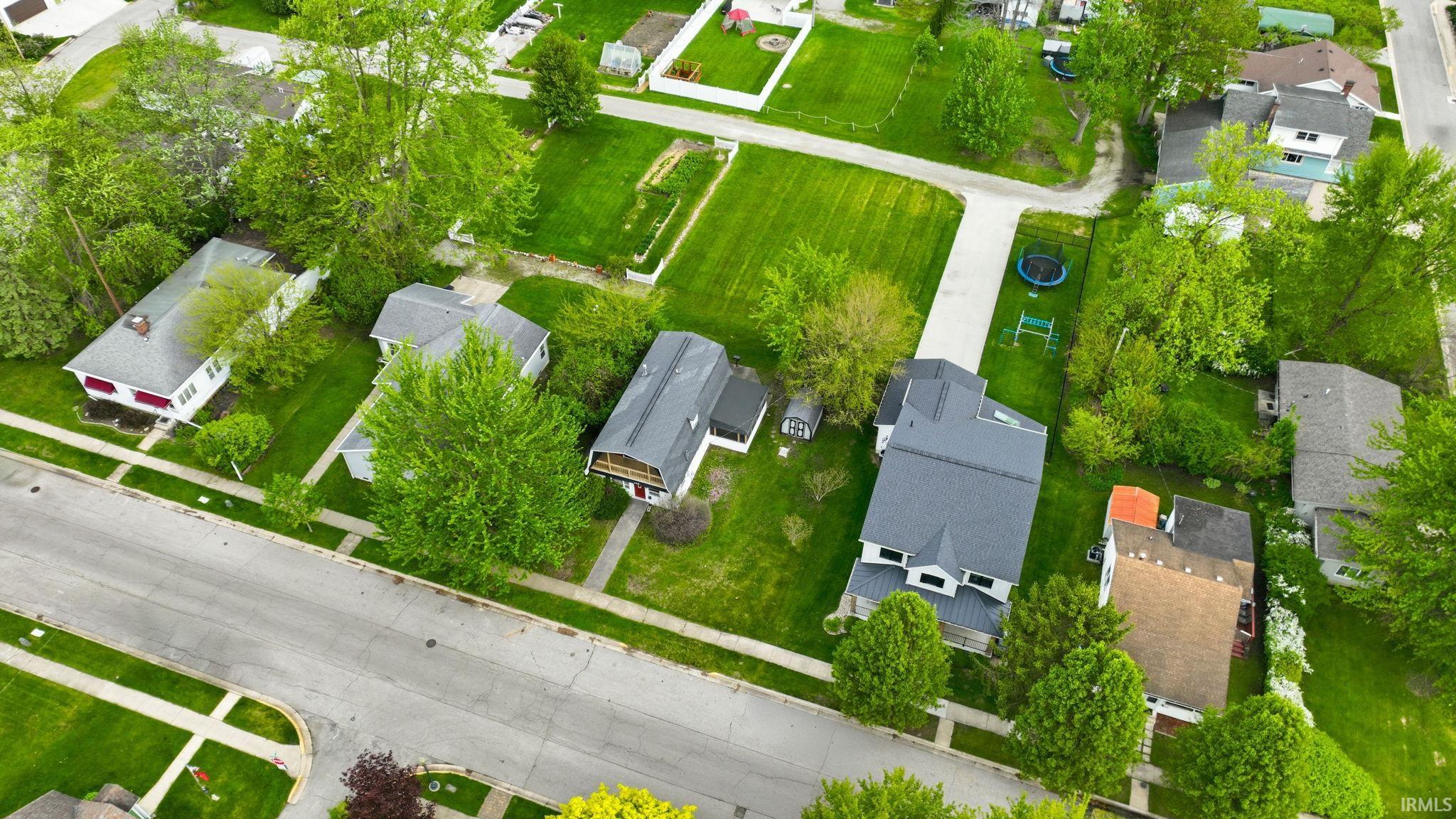 Neighborhood aerial showcasing multiple properties with green lawns and mature trees