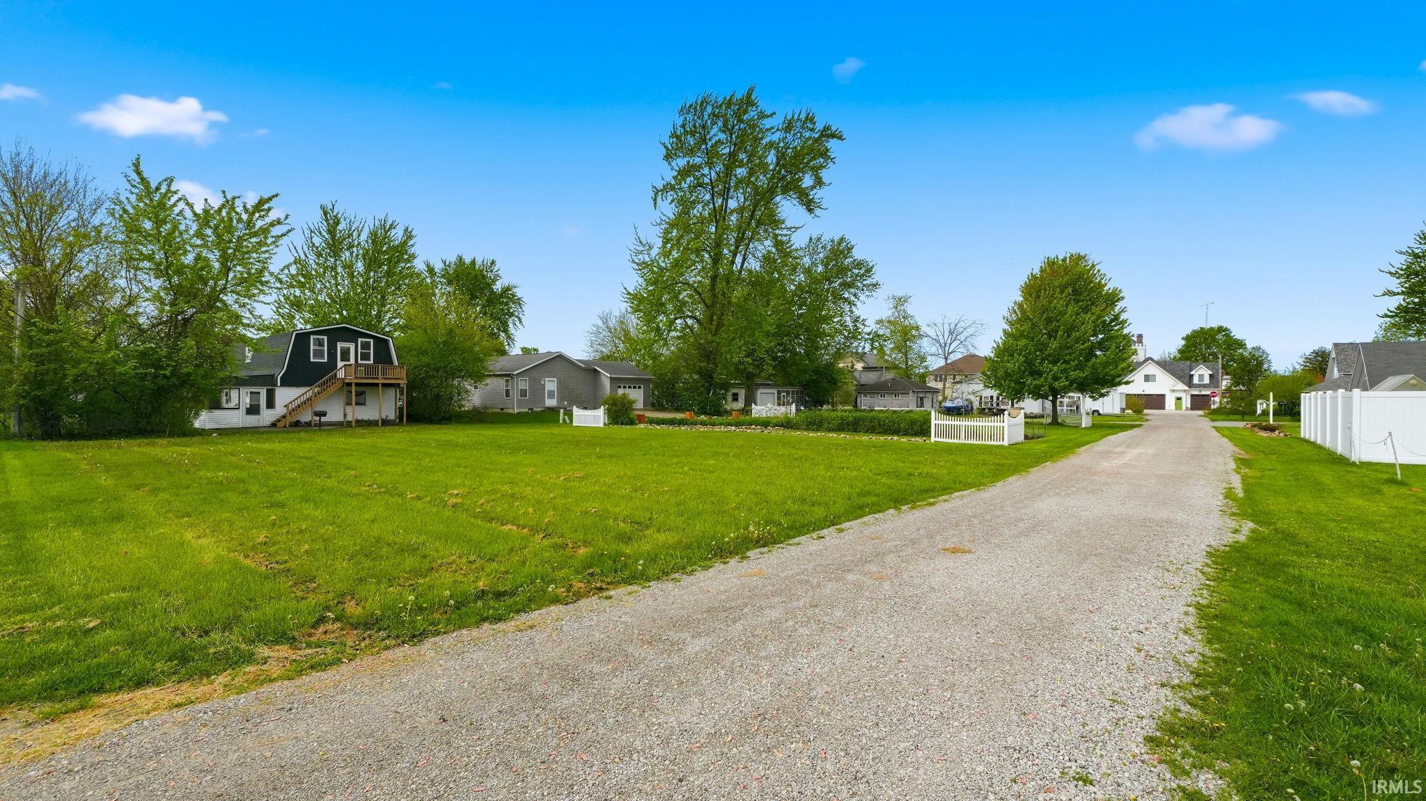 Expansive gravel driveway bordered by lush green lawns
