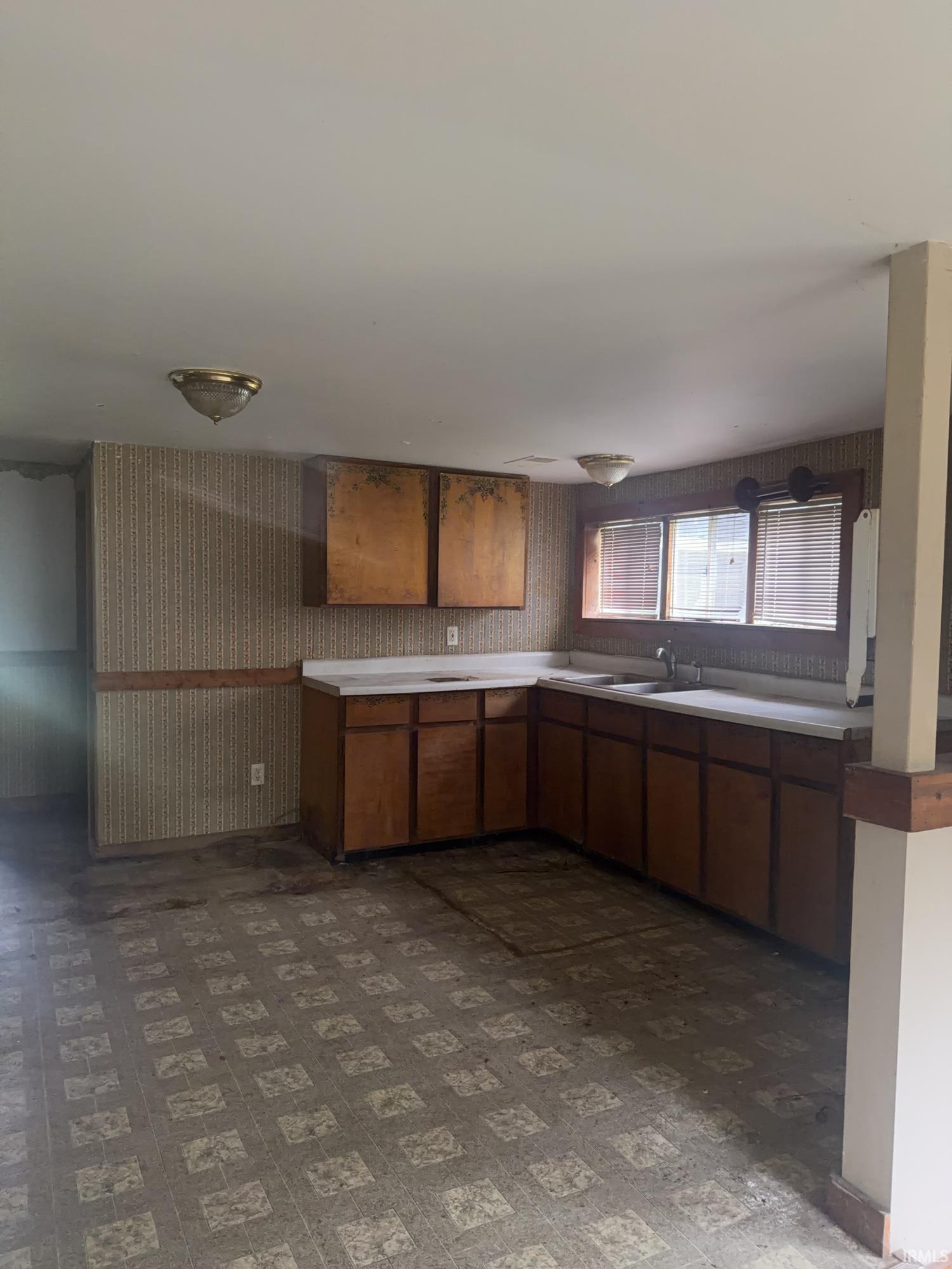 Kitchen space featuring a corner sink, upper and lower cabinetry, and two windows