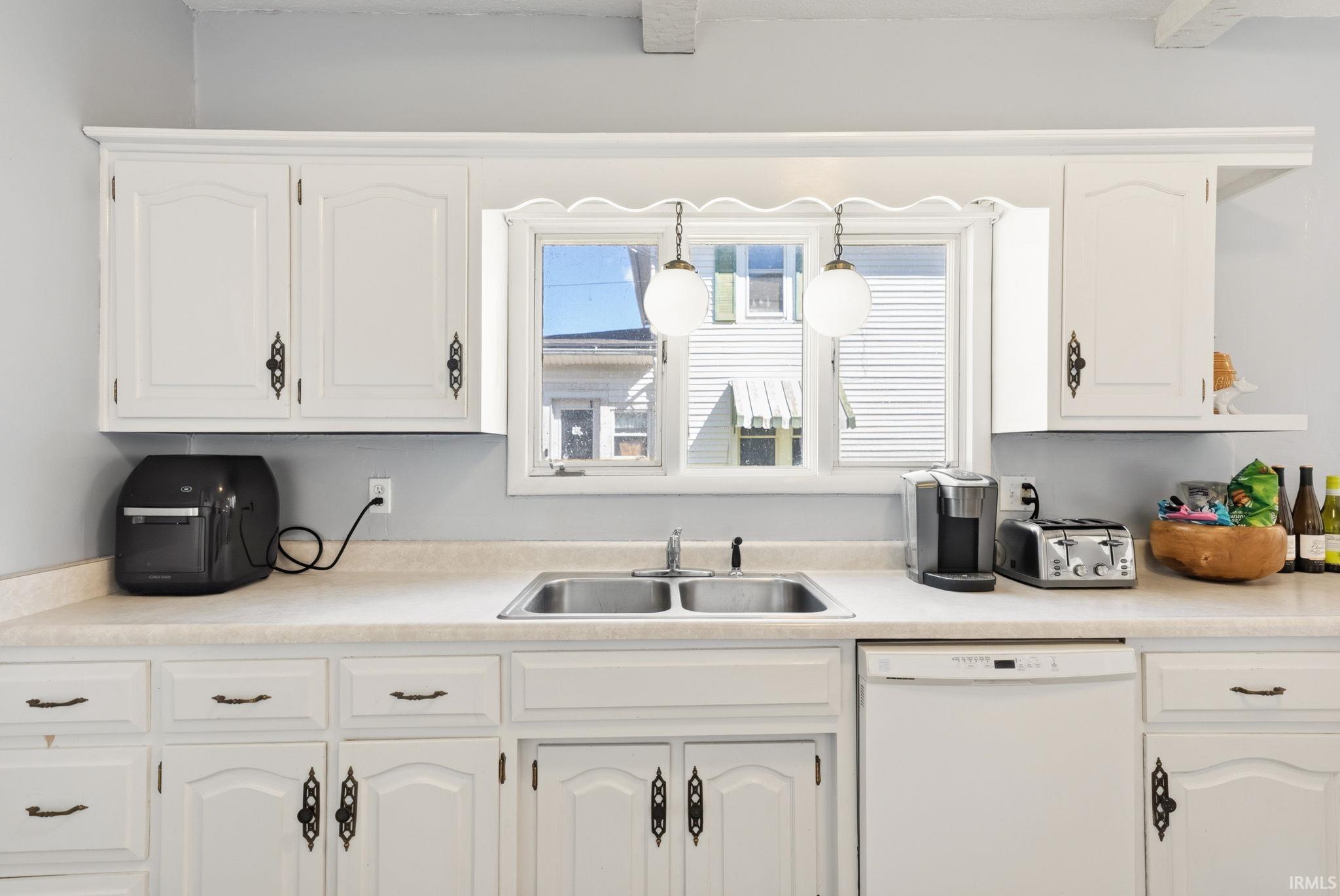 Kitchen with dishwasher, light countertops, and white cabinets