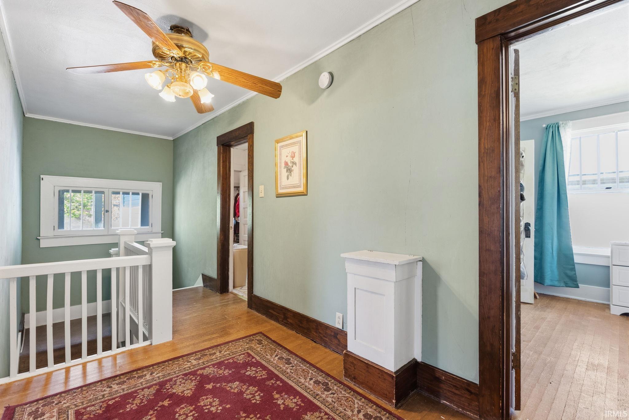 Hall with light wood-style flooring, healthy amount of natural light, an upstairs landing, and ornamental molding