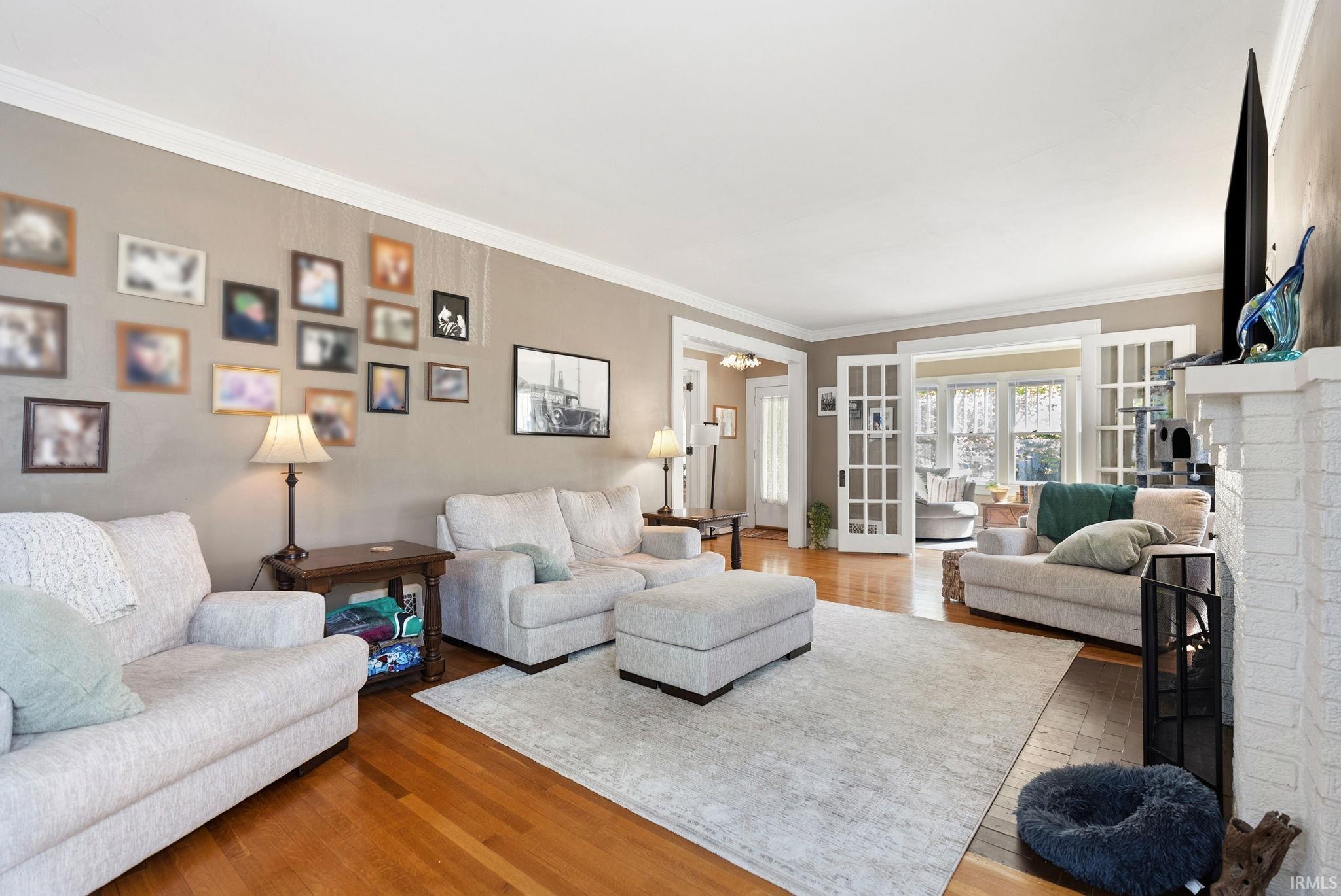 Living room with wood finished floors, ornamental molding, and a fireplace