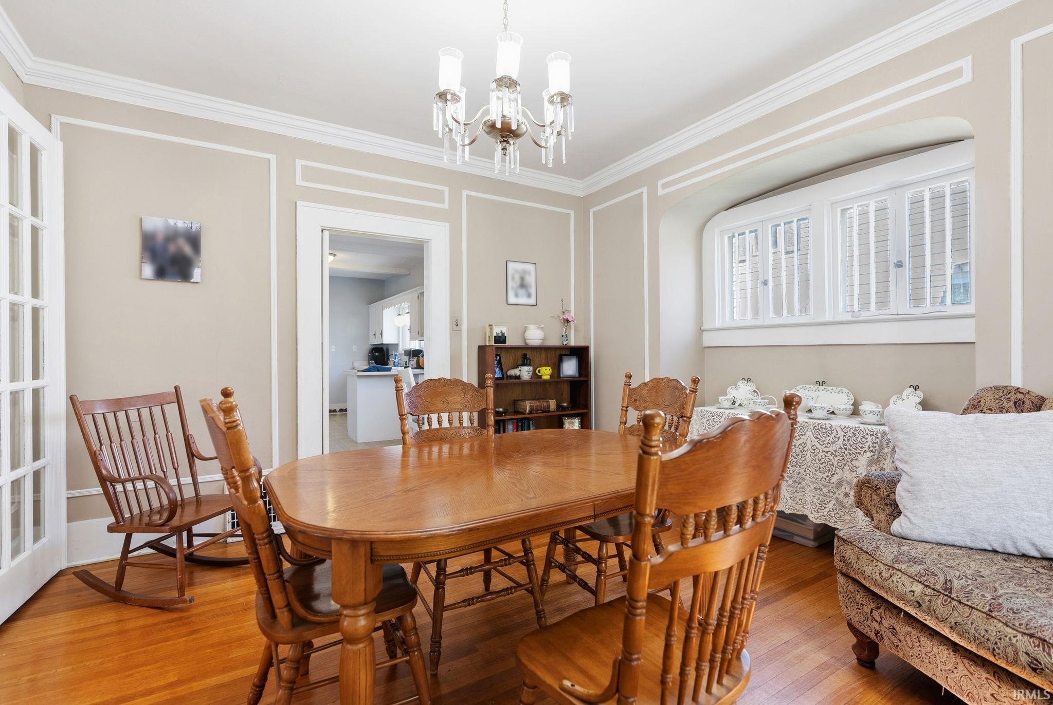 Dining space featuring wood finished floors, hanging lights, and ornamental molding
