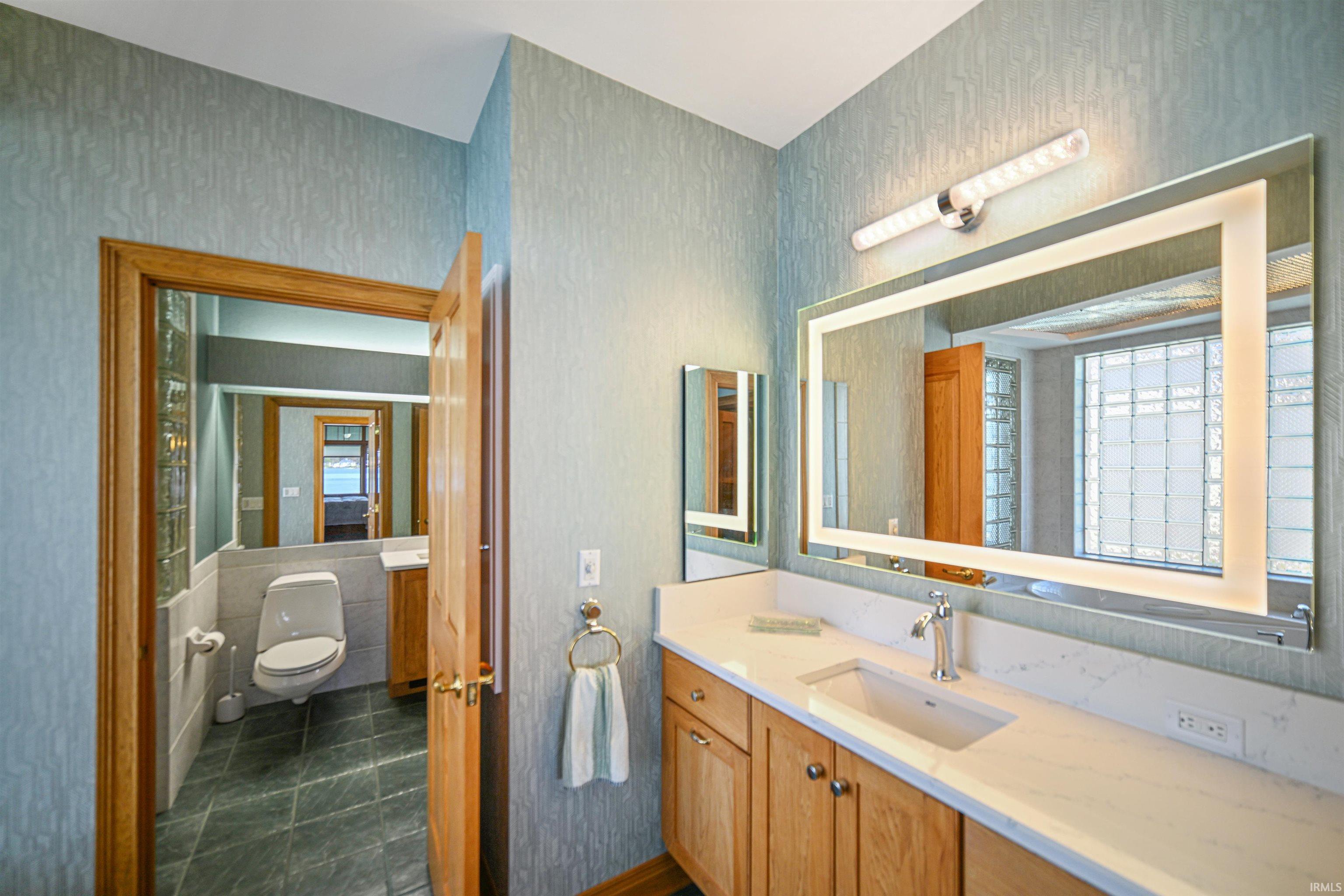 Bathroom vanity featuring wood cabinetry, a light-toned countertop, and an undermount sink with a chrome faucet