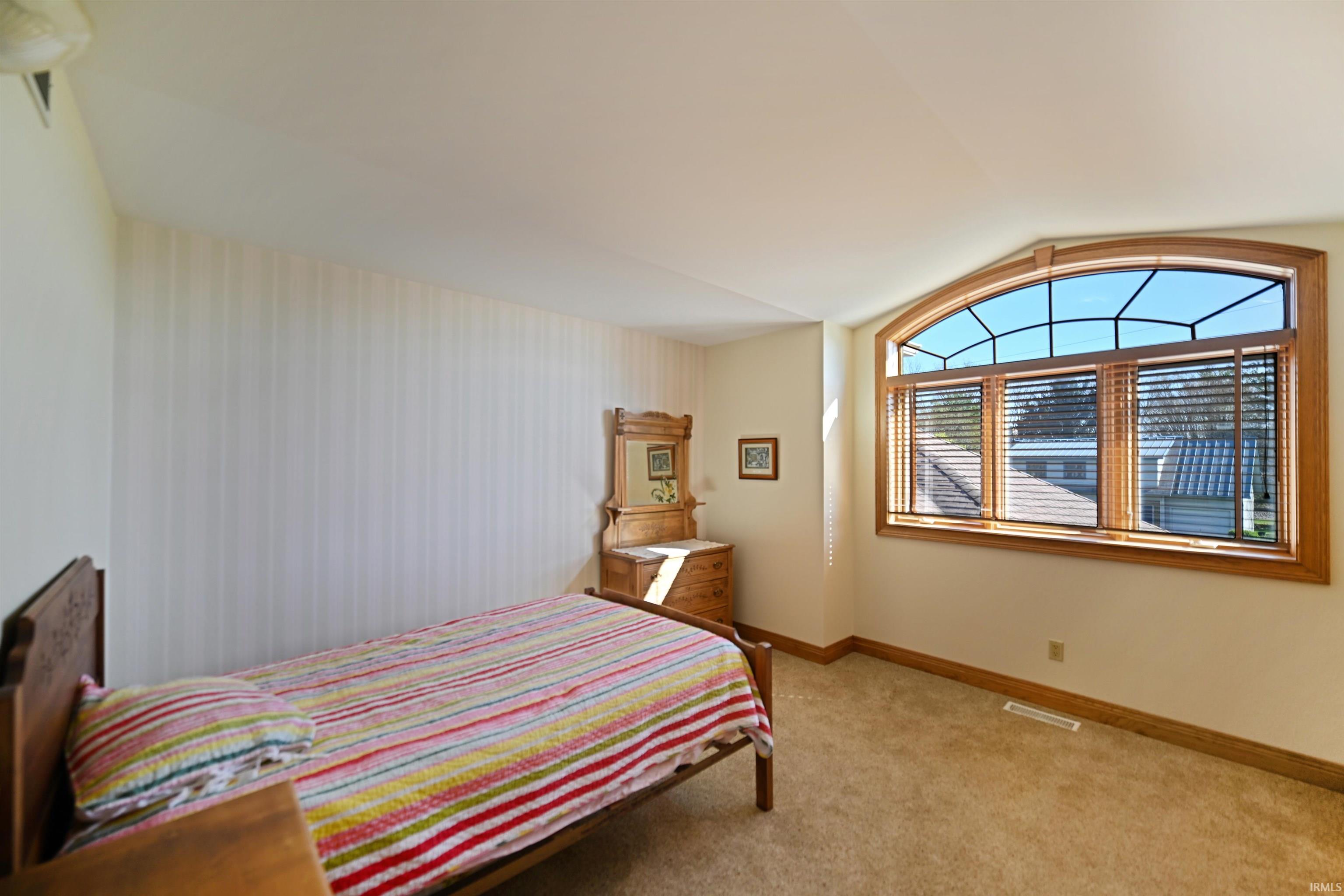Arched window with wood trim, featuring integrated blinds