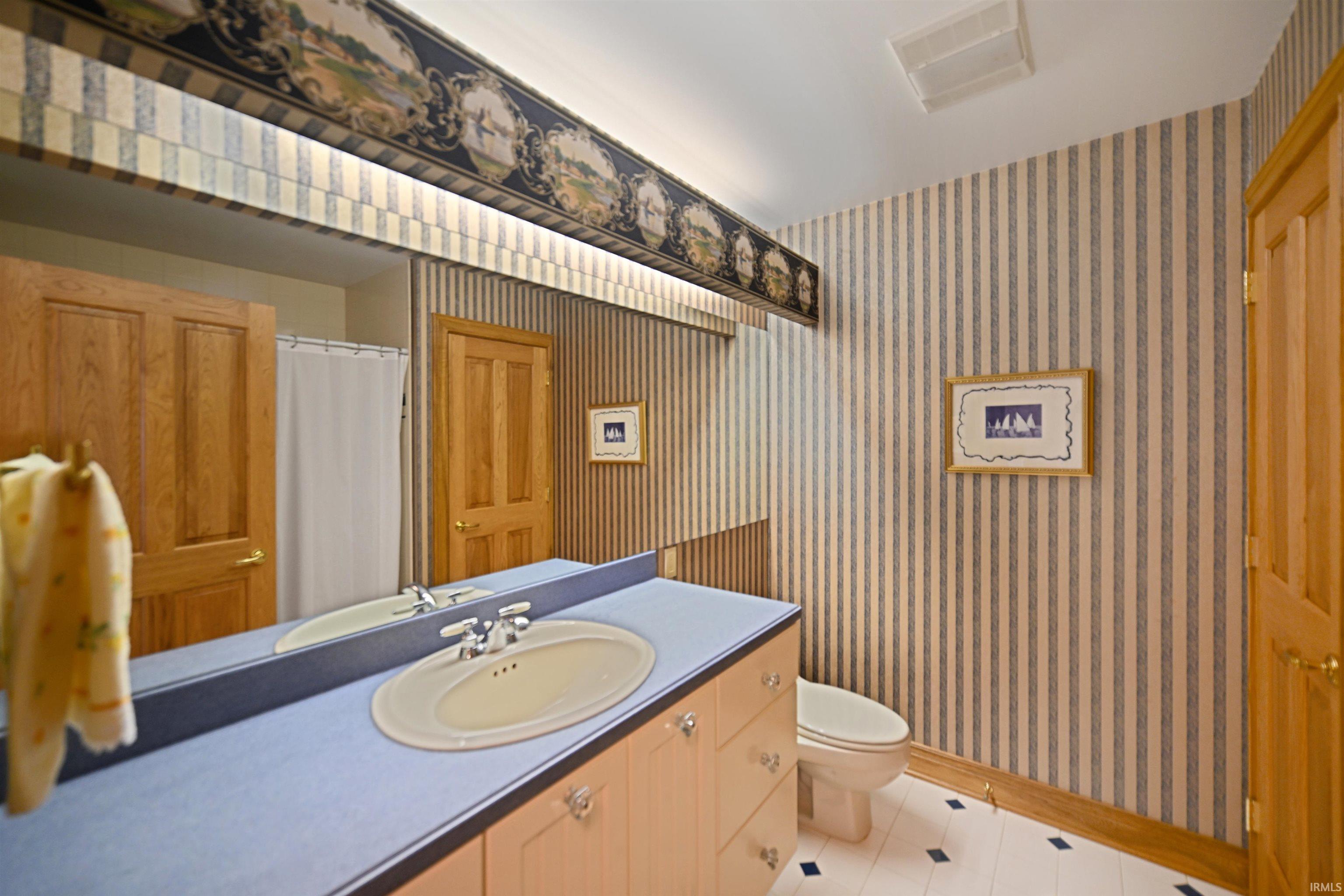 Bathroom featuring a light wood vanity, an oval sink with a chrome faucet, and a full-width mirror