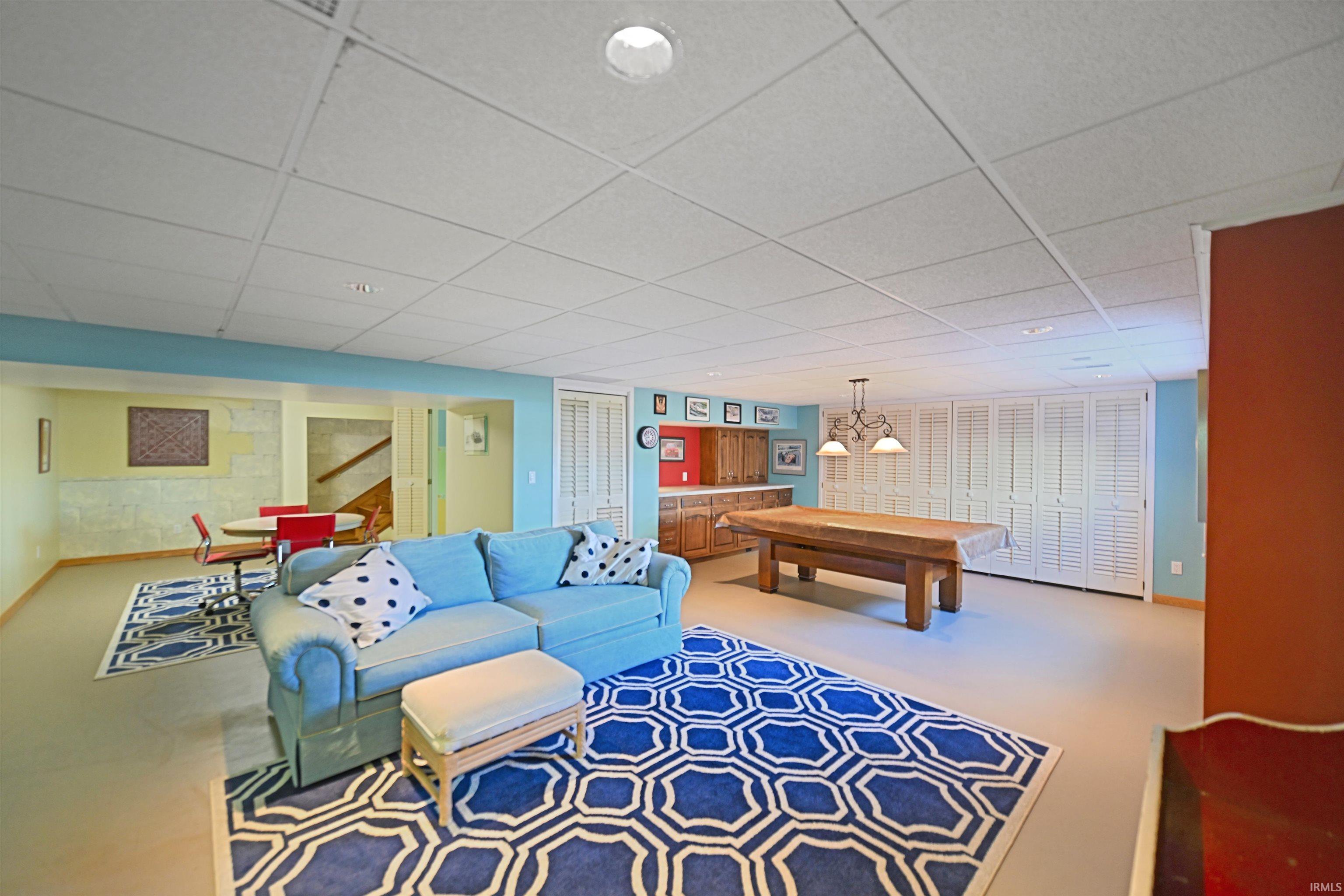 Spacious recreation area featuring a drop ceiling, light-colored flooring, and built-in shaker-style cabinetry