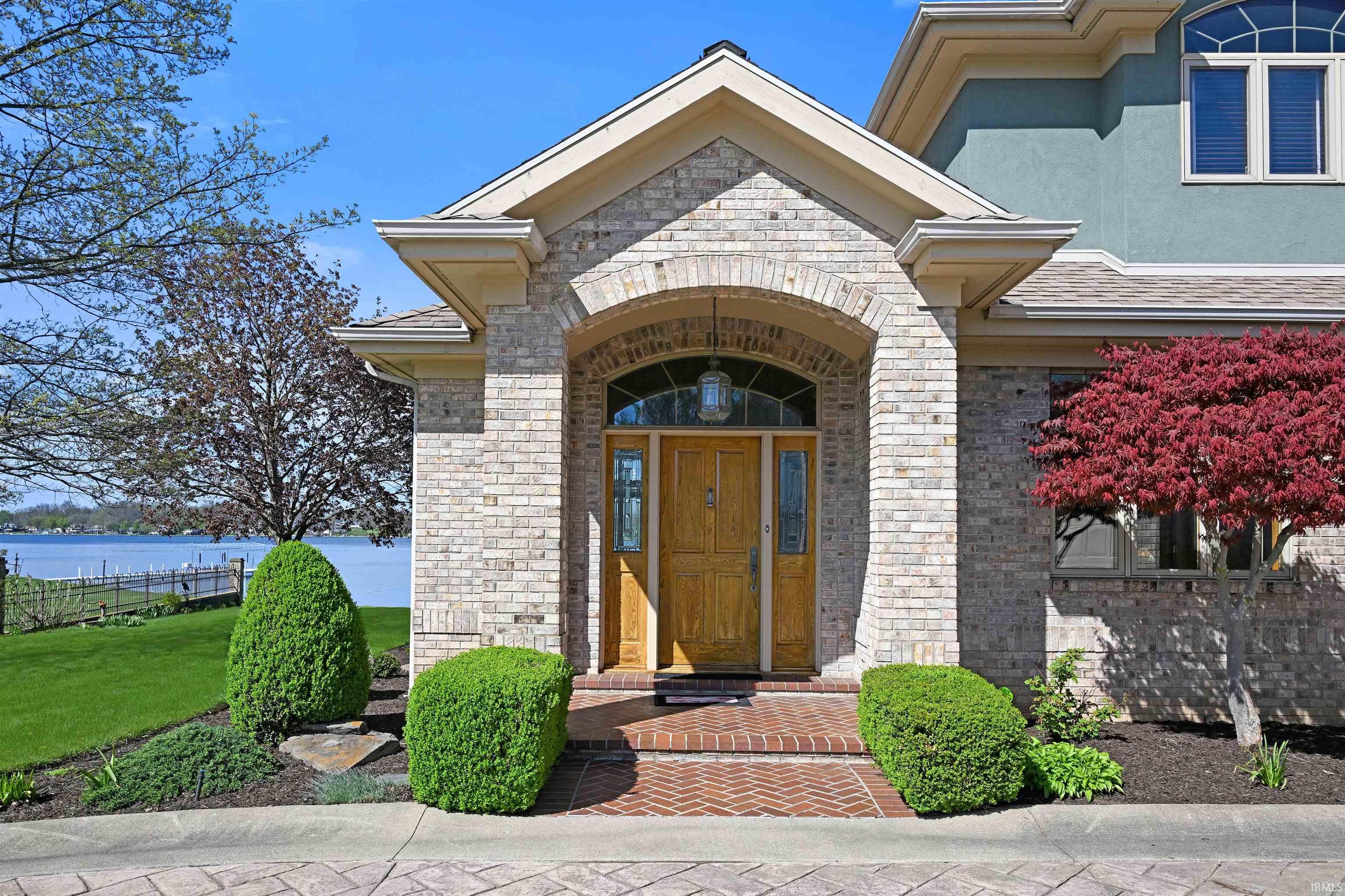 Brick facade entry with an arched portico, a wooden door, and transom window