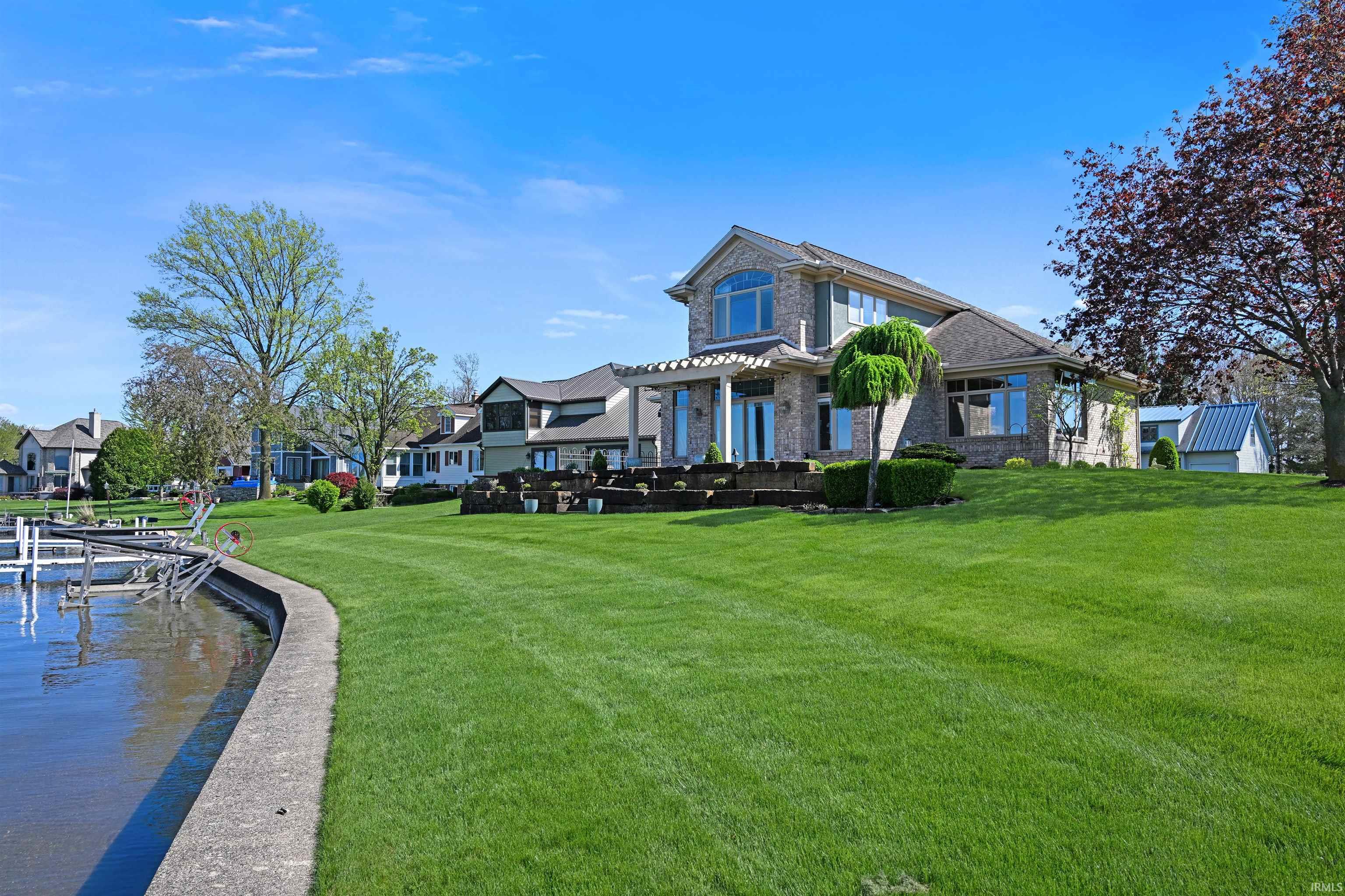 Brick and siding exterior residence featuring multiple large windows, a terraced outdoor living space, and a white pergola