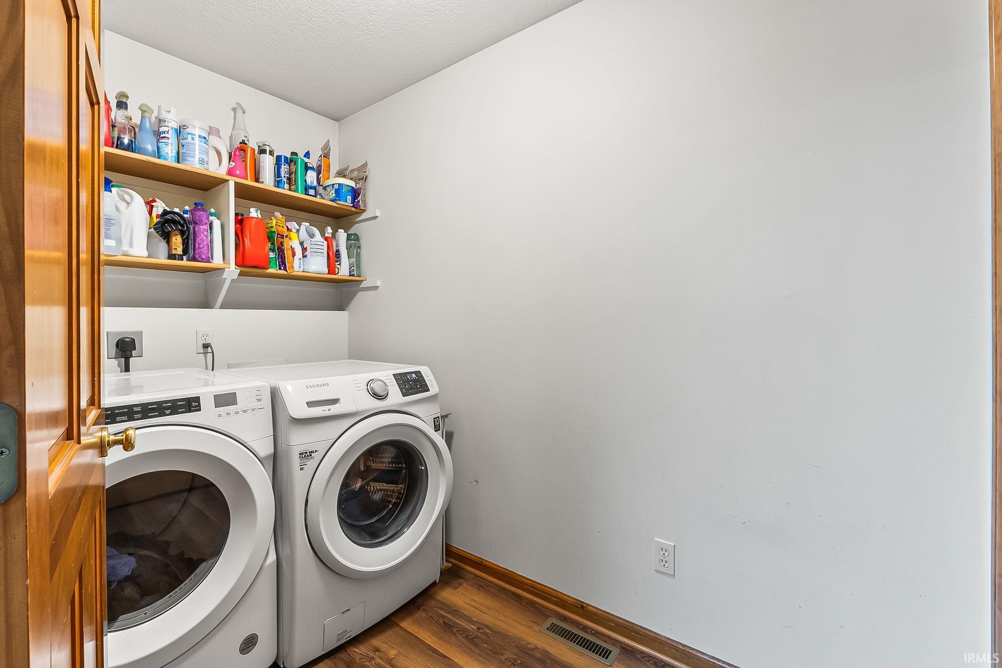 Laundry area featuring wood-finish flooring, white walls, and built-in shelving