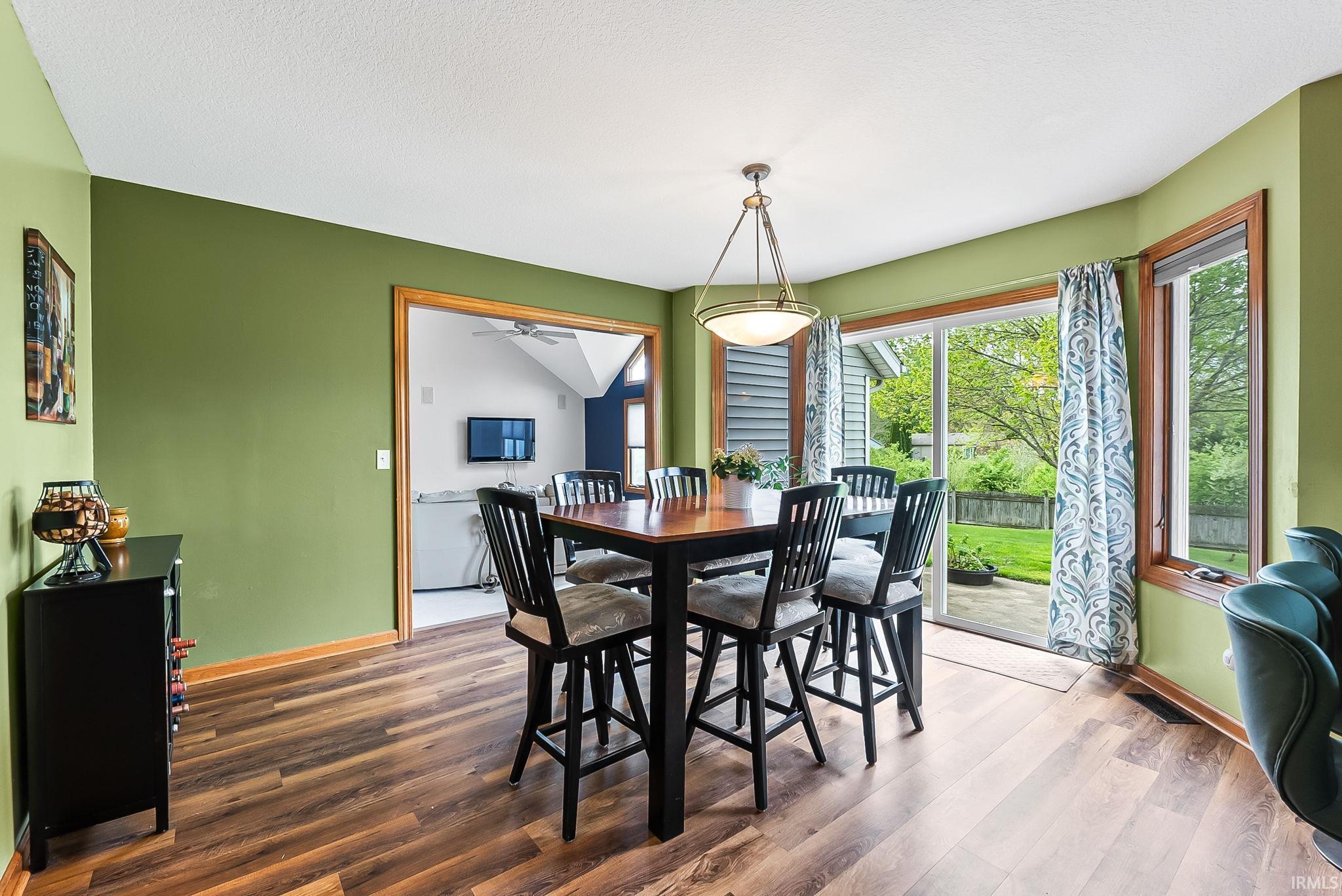 Dining area featuring wood-finish flooring, a contemporary ceiling light fixture, and a sliding glass door leading to an outdoor patio