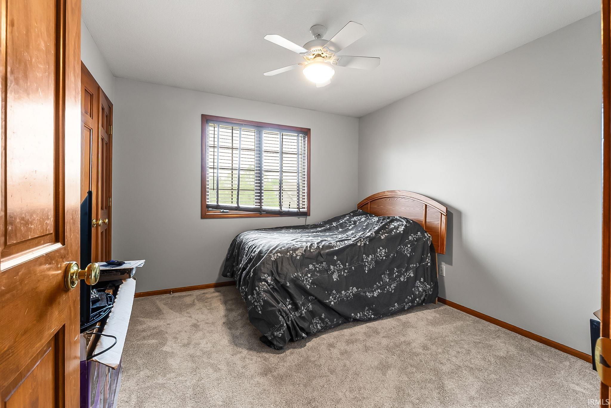 Comfortable room featuring wood-finish trim, a window with blinds, and a ceiling fan with integrated lighting