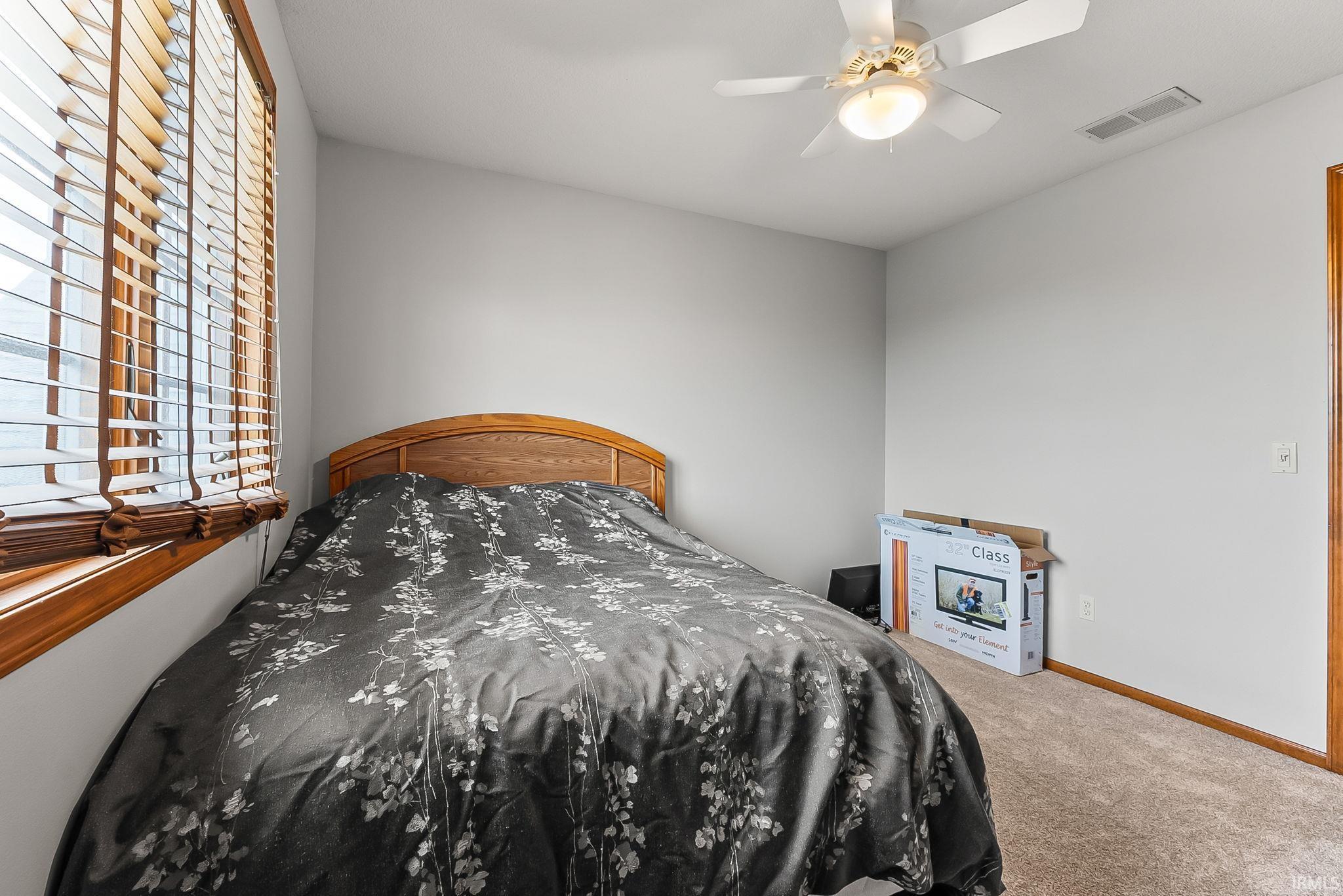 Room featuring a ceiling fan with integrated lighting, wood-finish window blinds, and carpet flooring