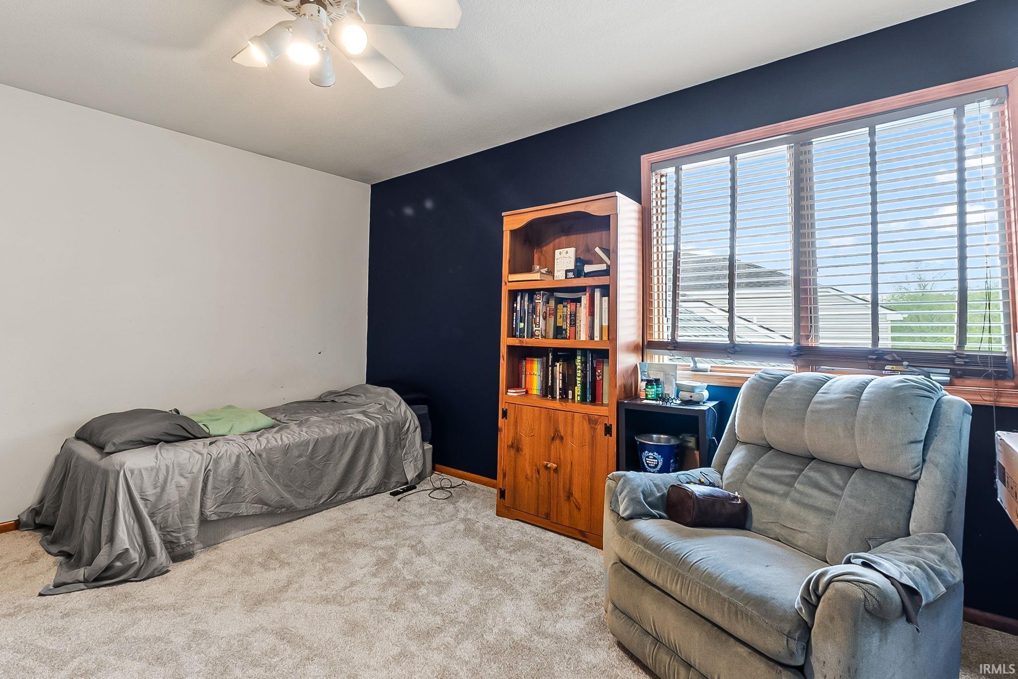 Carpeted room featuring a ceiling fan, a window with wood-finish blinds, and a two-tone wall treatment