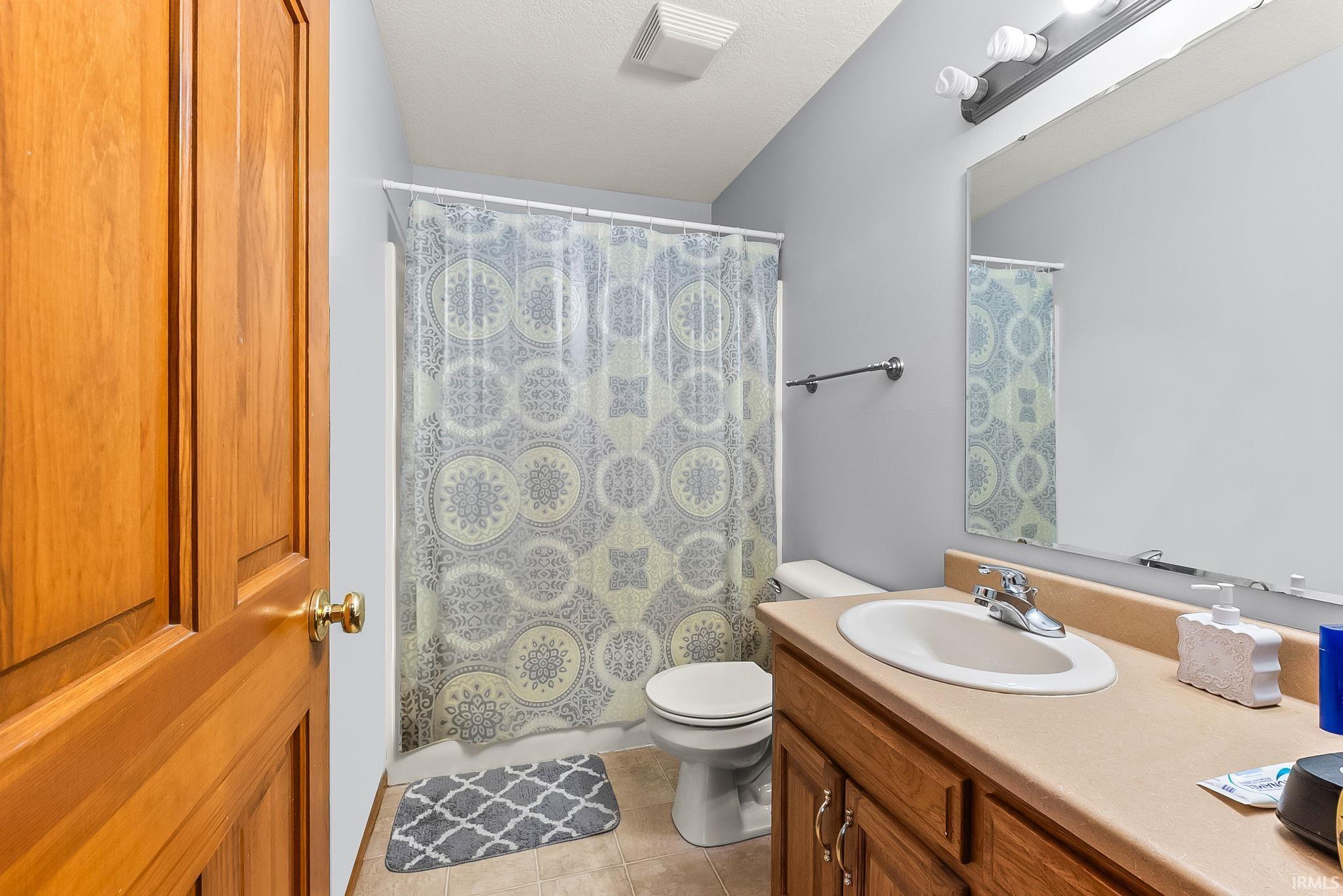 Bathroom featuring a wood-finish vanity with an integrated sink and light-toned countertop