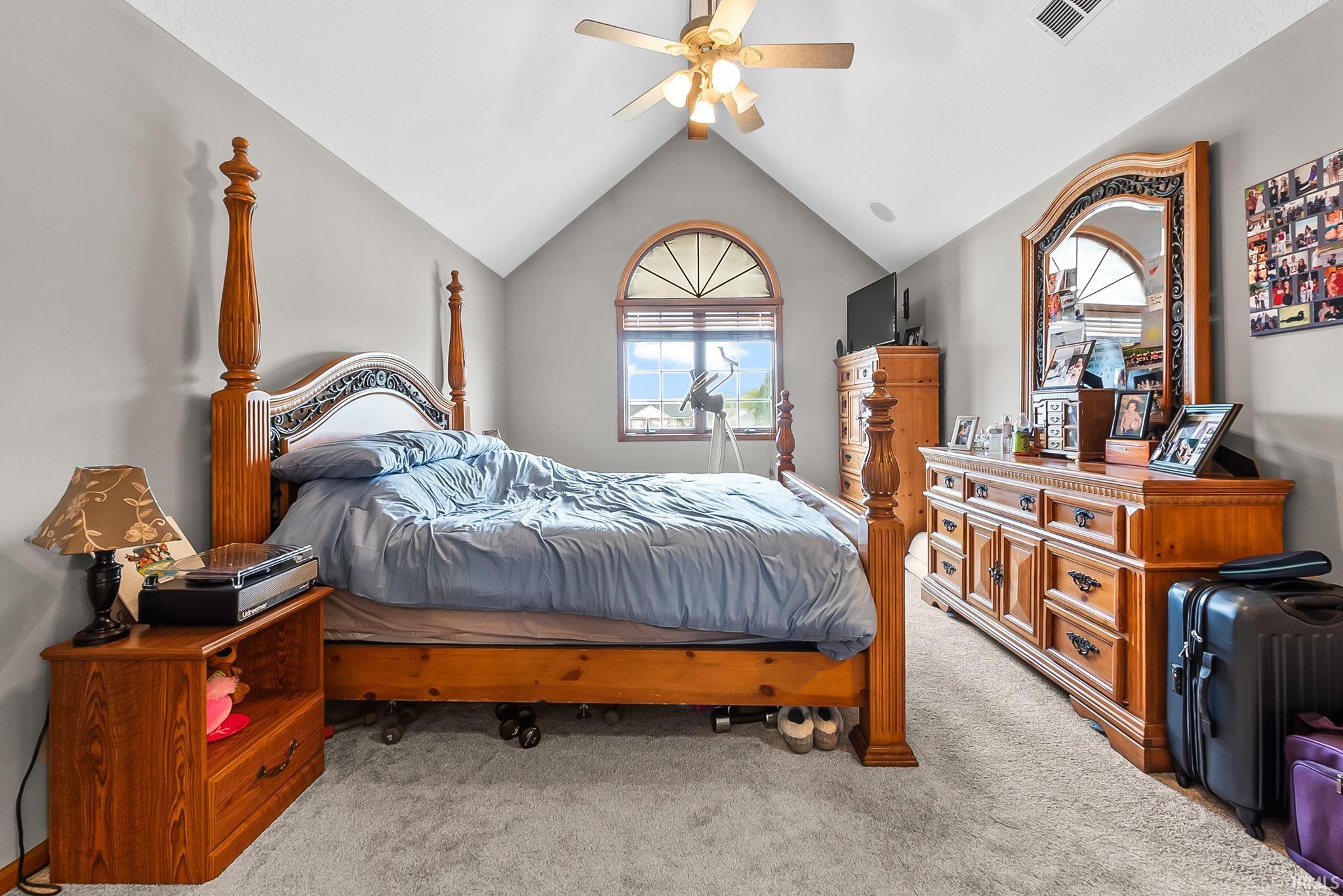 Bedroom featuring a vaulted ceiling, arched window with upper transom, and light gray wall paint