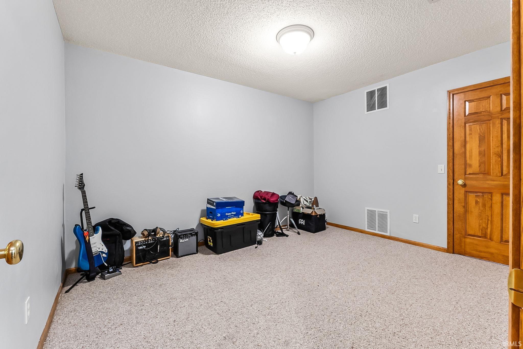 Carpeted room featuring light gray walls, a textured ceiling, and a flush mount ceiling light fixture