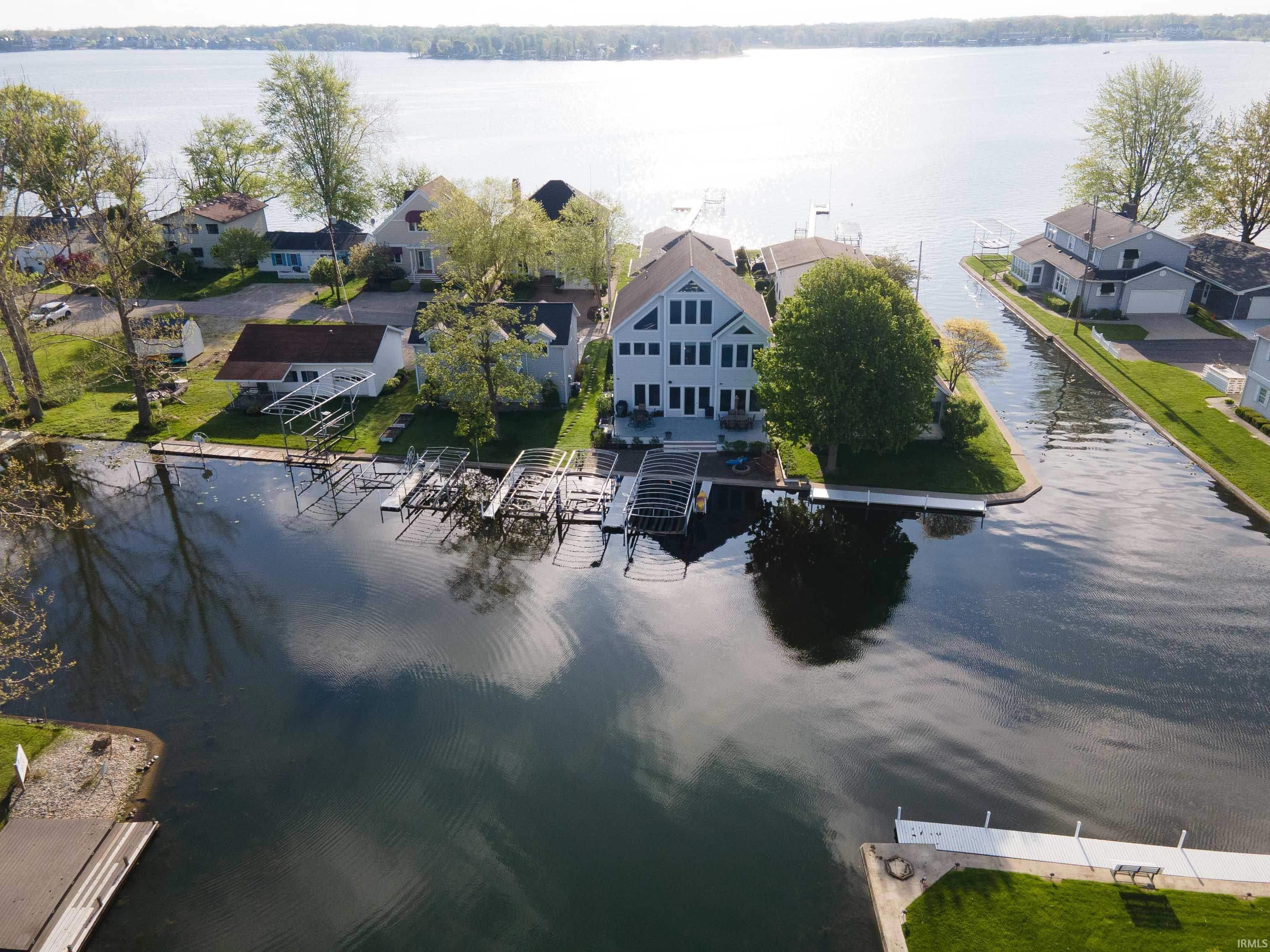 Waterfront property featuring a multi-story residence with multiple windows, boat docks, and a channel providing access to the main lake