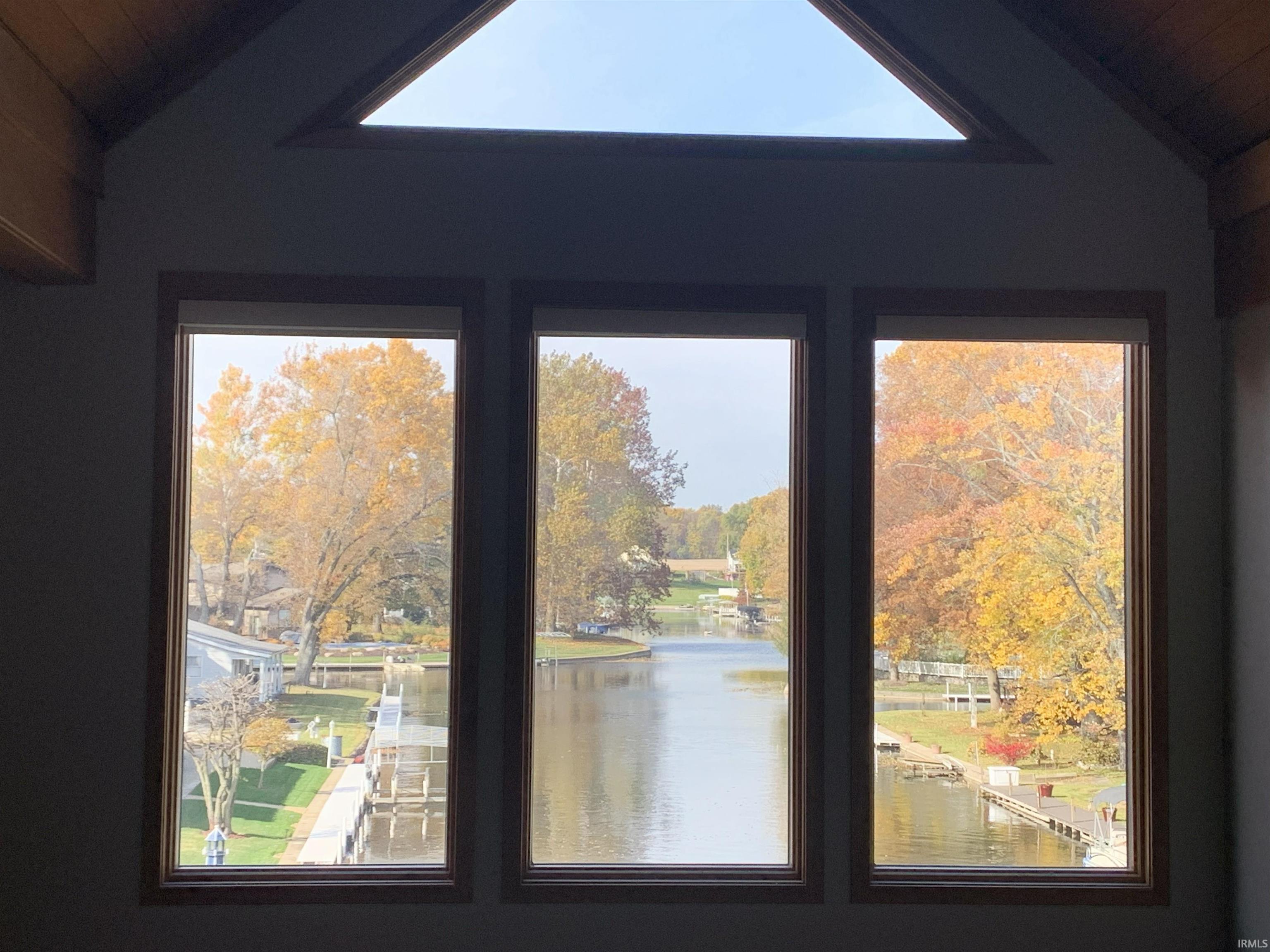 Vaulted ceiling with exposed wood beams and a triangular transom window