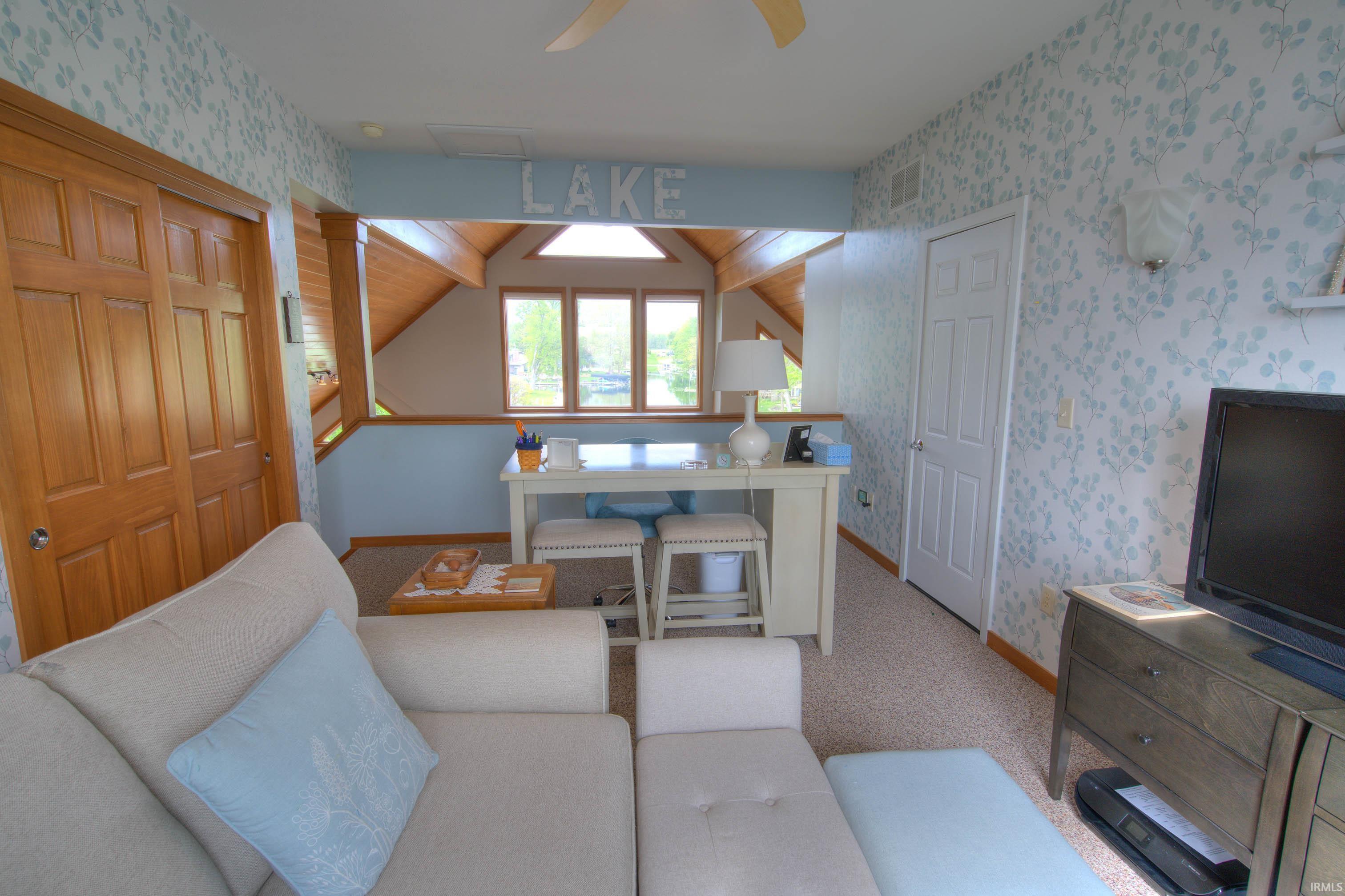 Carpeted room featuring a half-wall opening to an additional area with a window bank