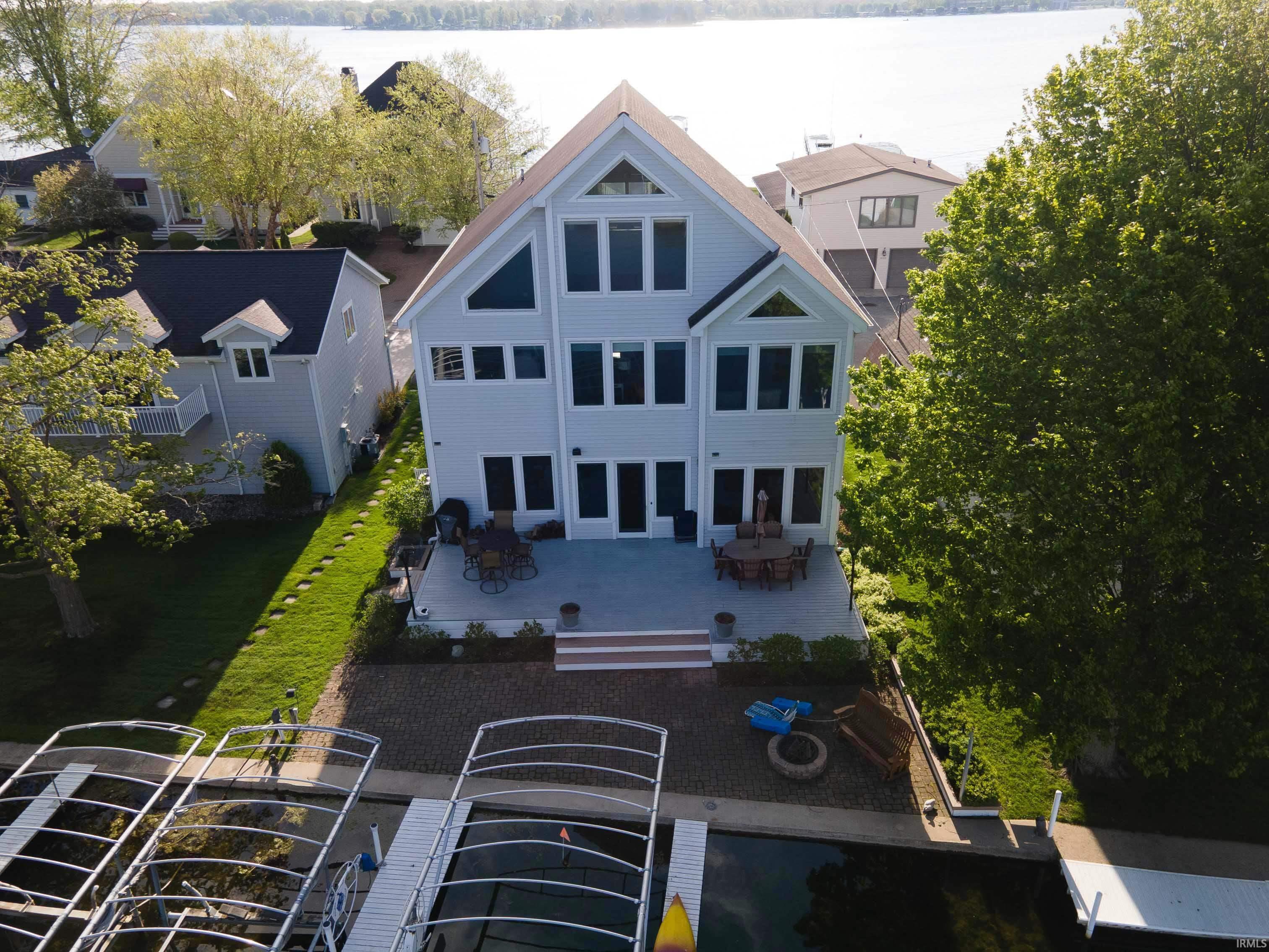 Waterside residence featuring multiple levels of windows, a spacious rear patio, and a dedicated boat dock