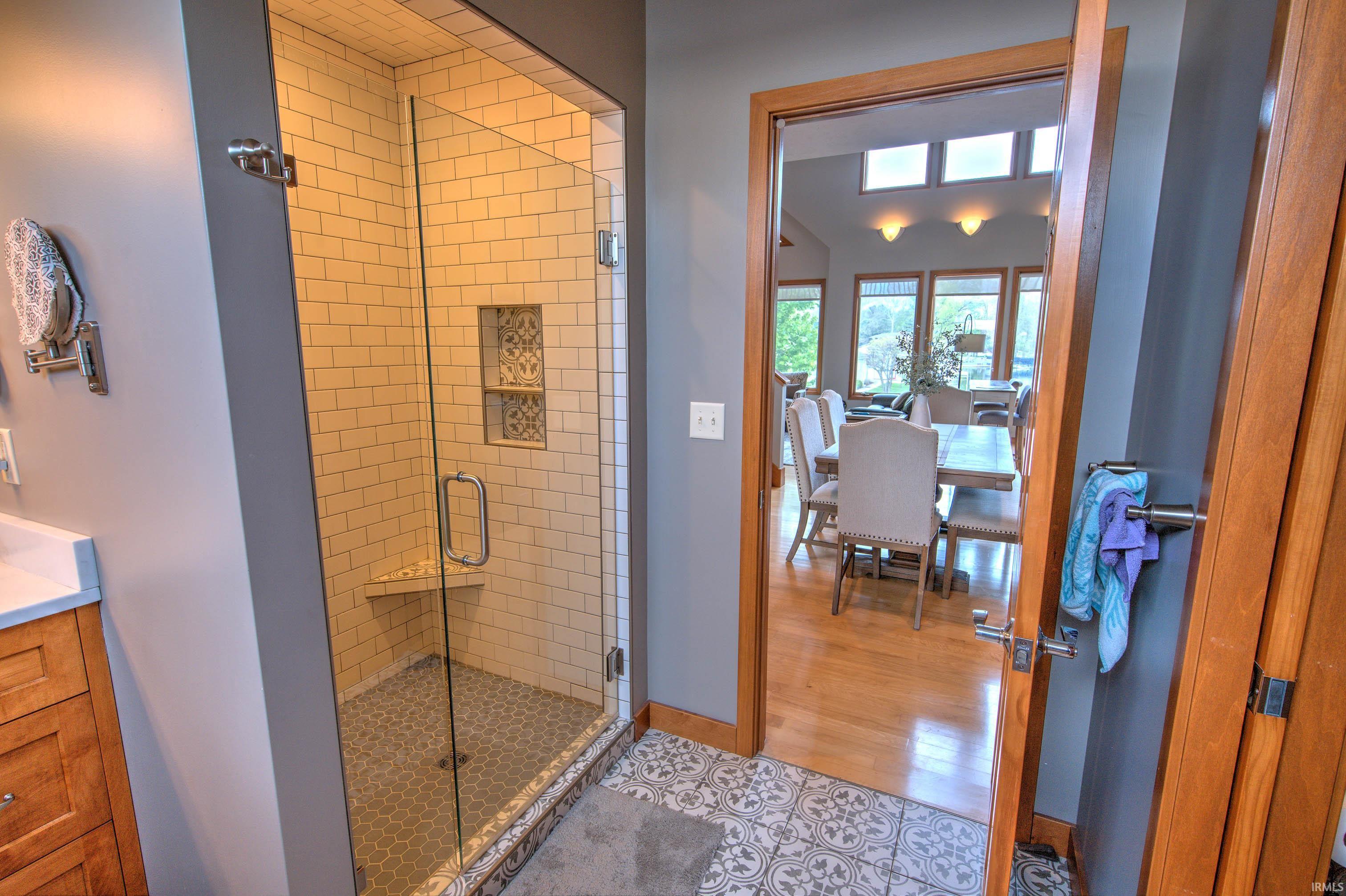 Glass-enclosed shower featuring subway tile walls, a built-in bench, and dual recessed niches