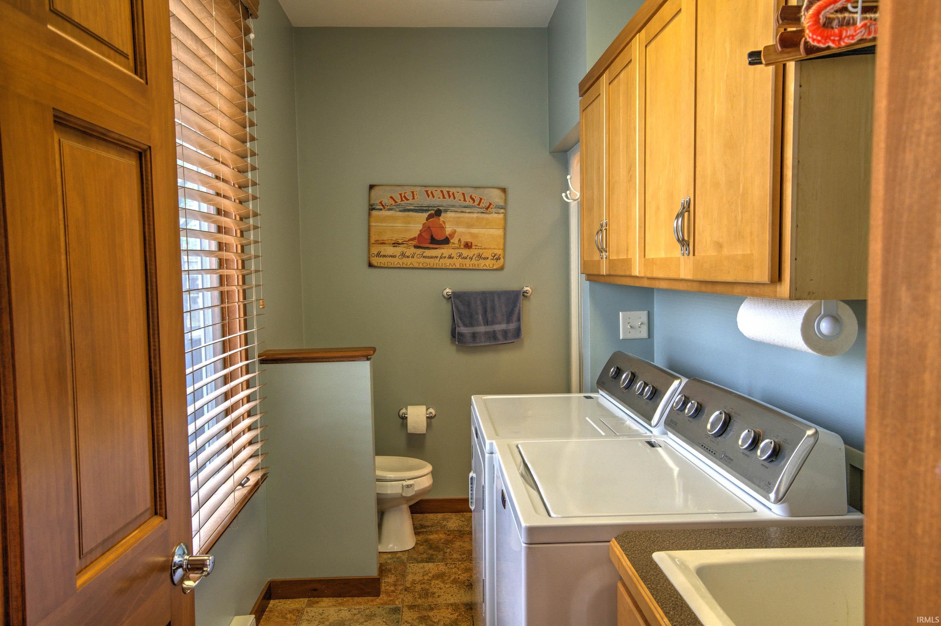 Utility room featuring a top-load washer, a front-load dryer, and wood-finish cabinetry