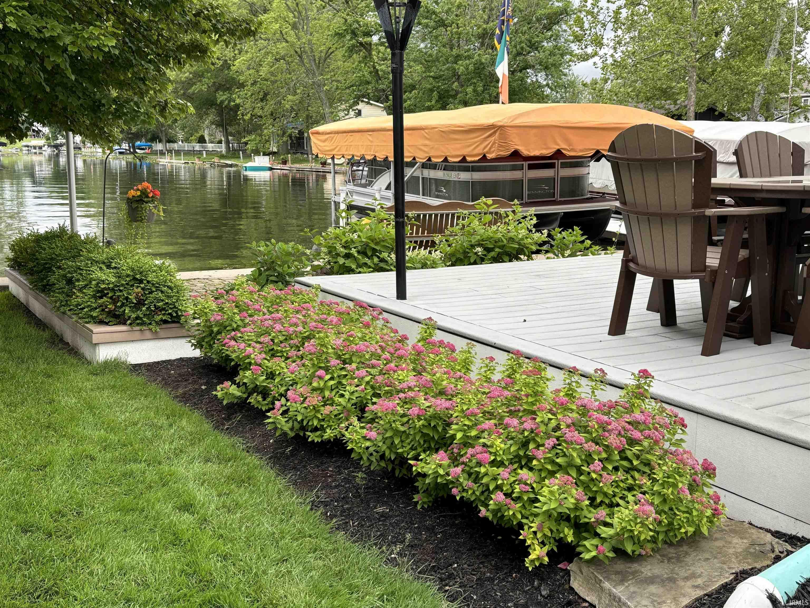 Waterfront composite deck featuring a built-in garden bed with flowering shrubs and manicured lawn